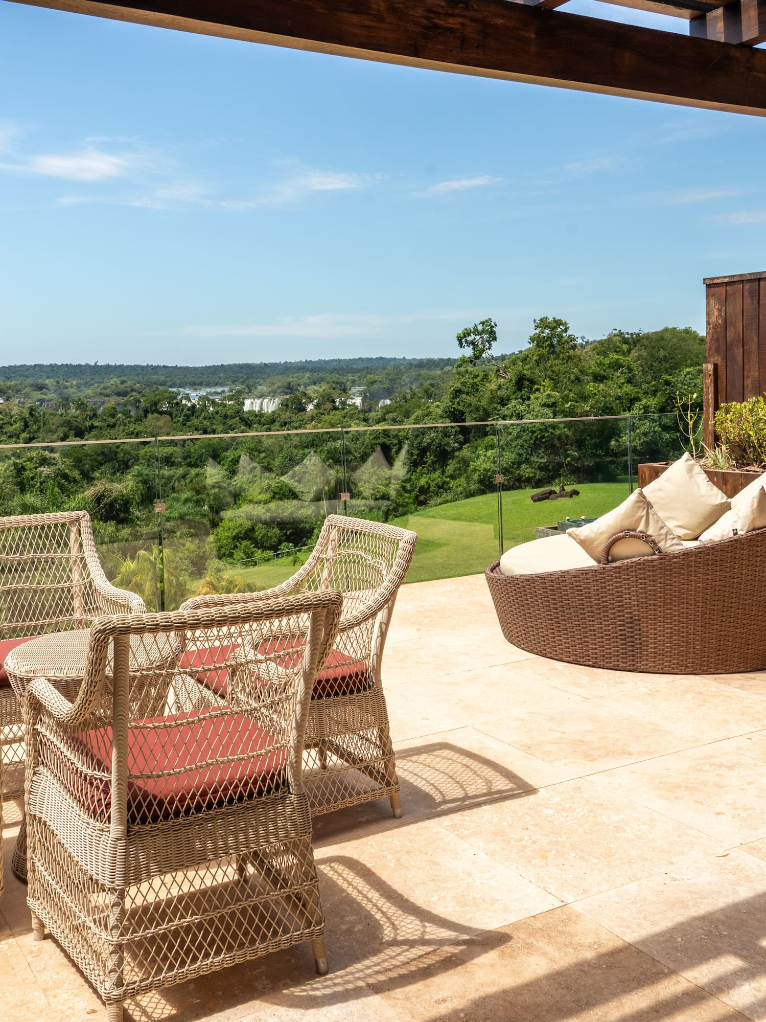 Luxury patio with wicker furniture, pergola, and distant Iguazu Falls.