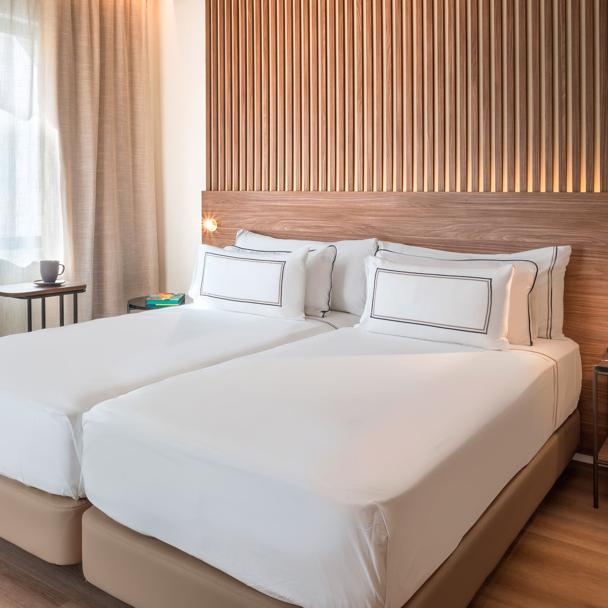 a bed with white sheets and a wood headboard