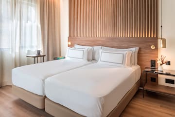 a bed with white sheets and a wood headboard