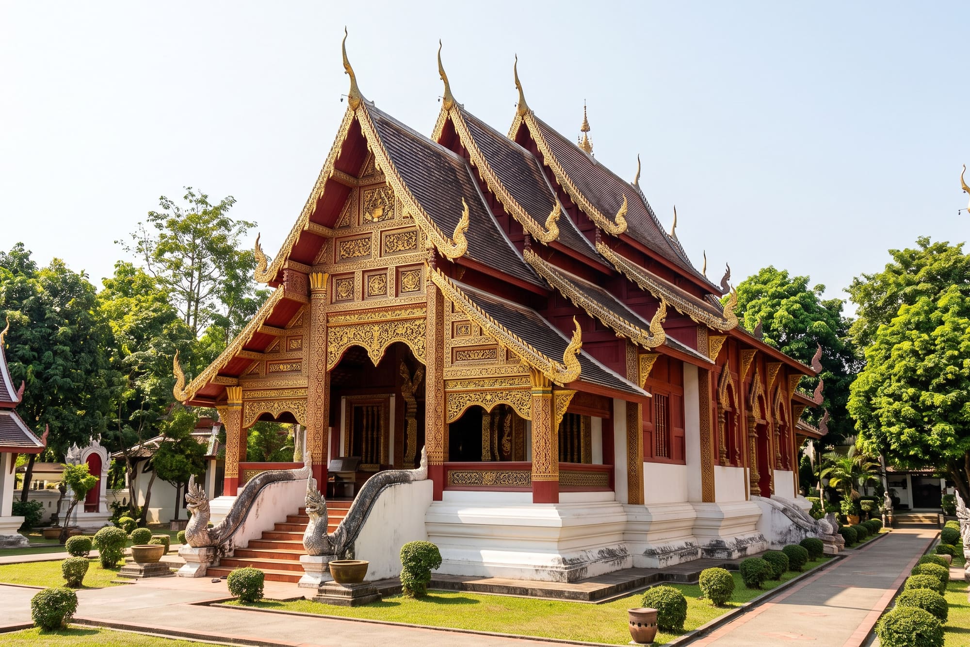 Ornate gold and red Thai temple with tiered roofs and naga steps, sunny day.