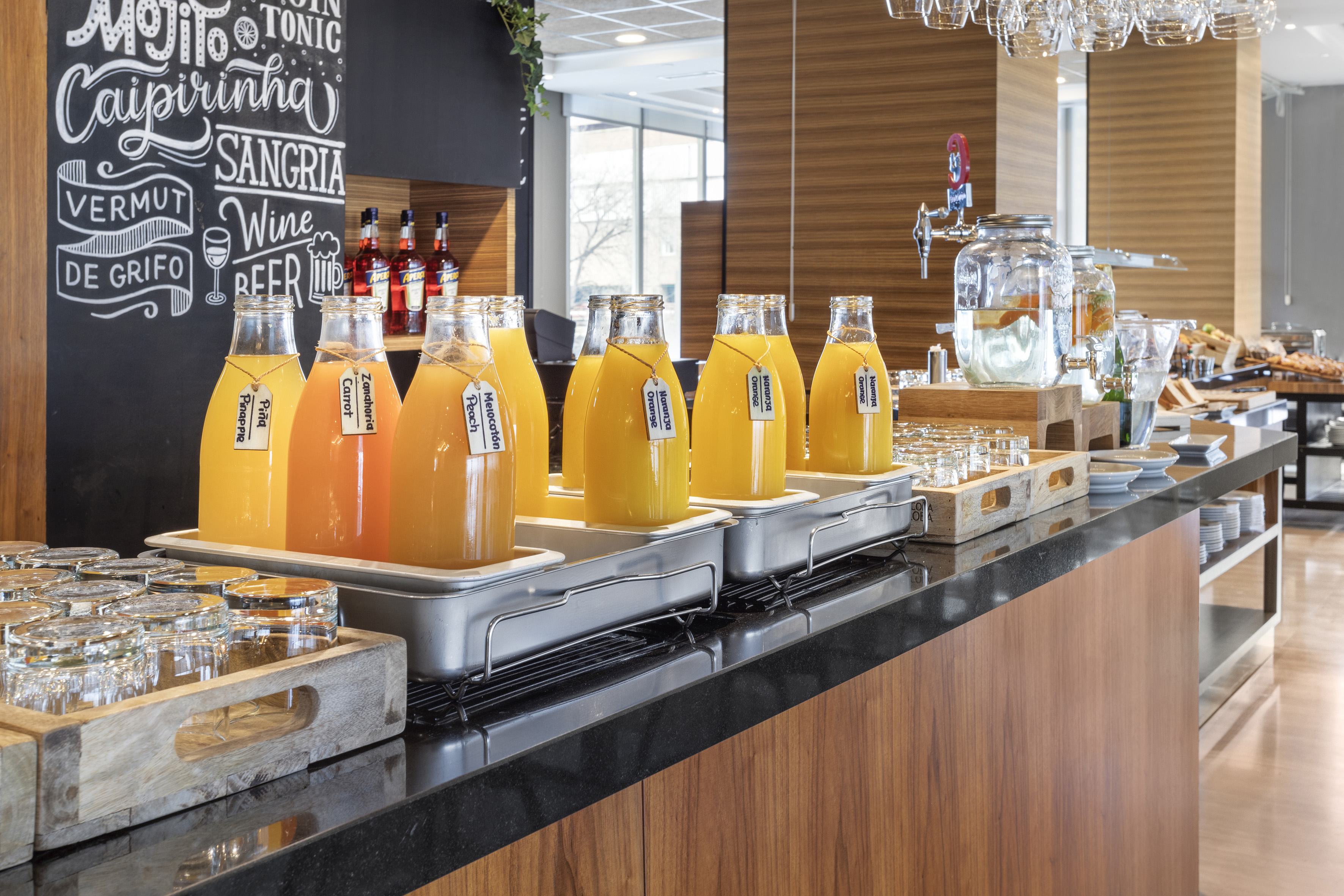 Fresh juice bar with varied fruit juices, infused water, and a drink menu chalkboard.