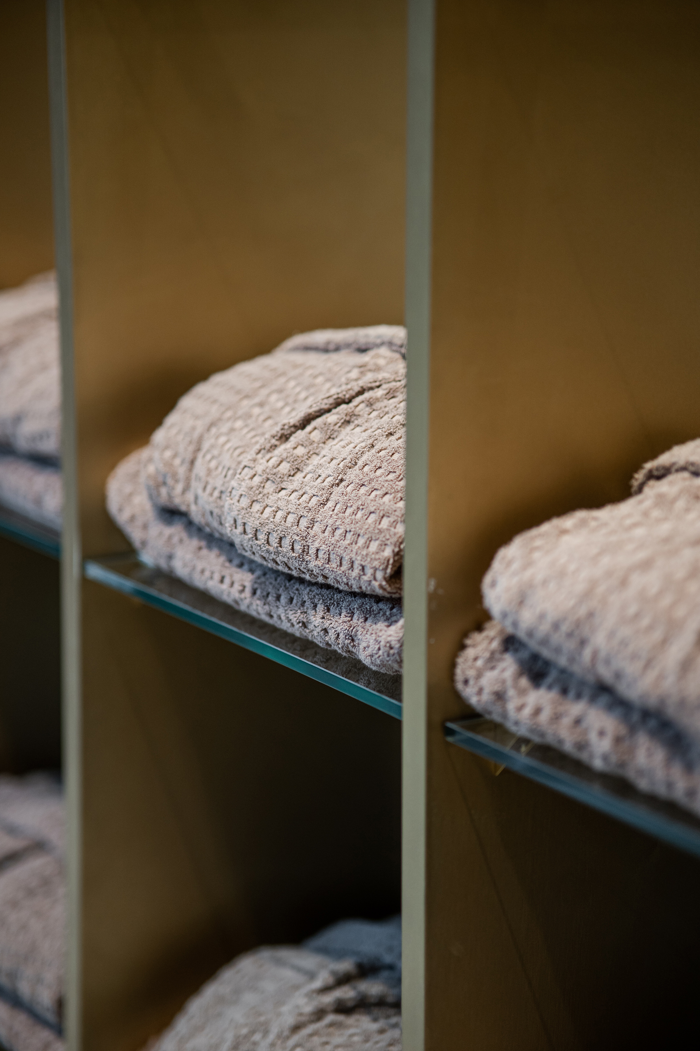 Grey waffle weave bath towels neatly folded on glass shelves.