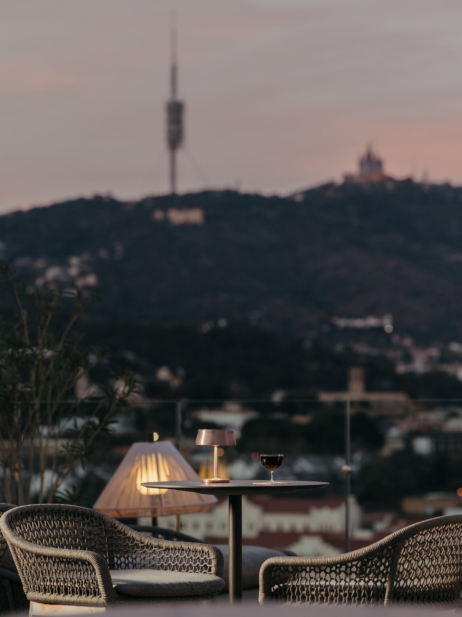 Copa de vino en terraza al atardecer con vista a la ciudad y Tibidabo.