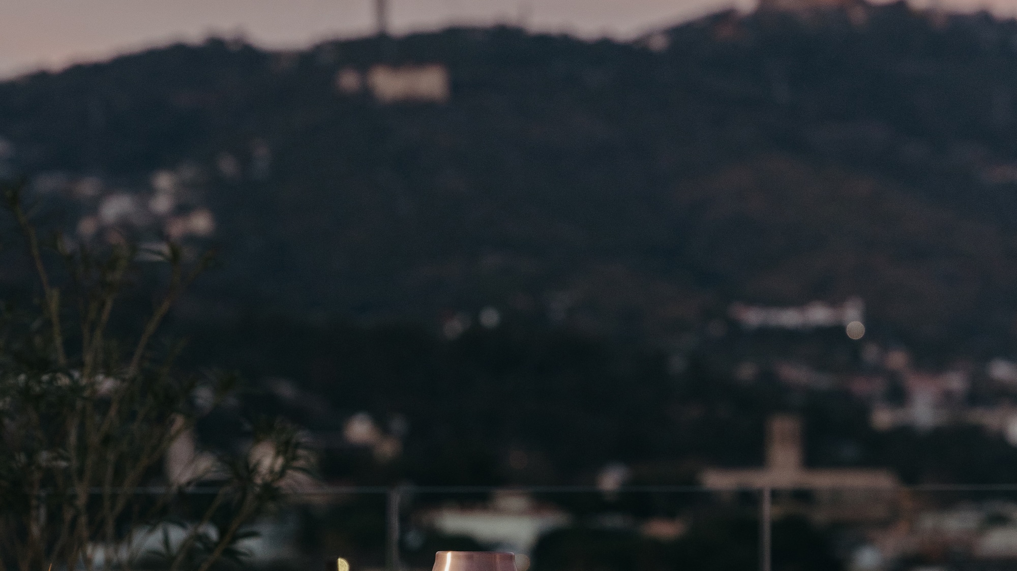 a table with a lamp and a glass of wine on it