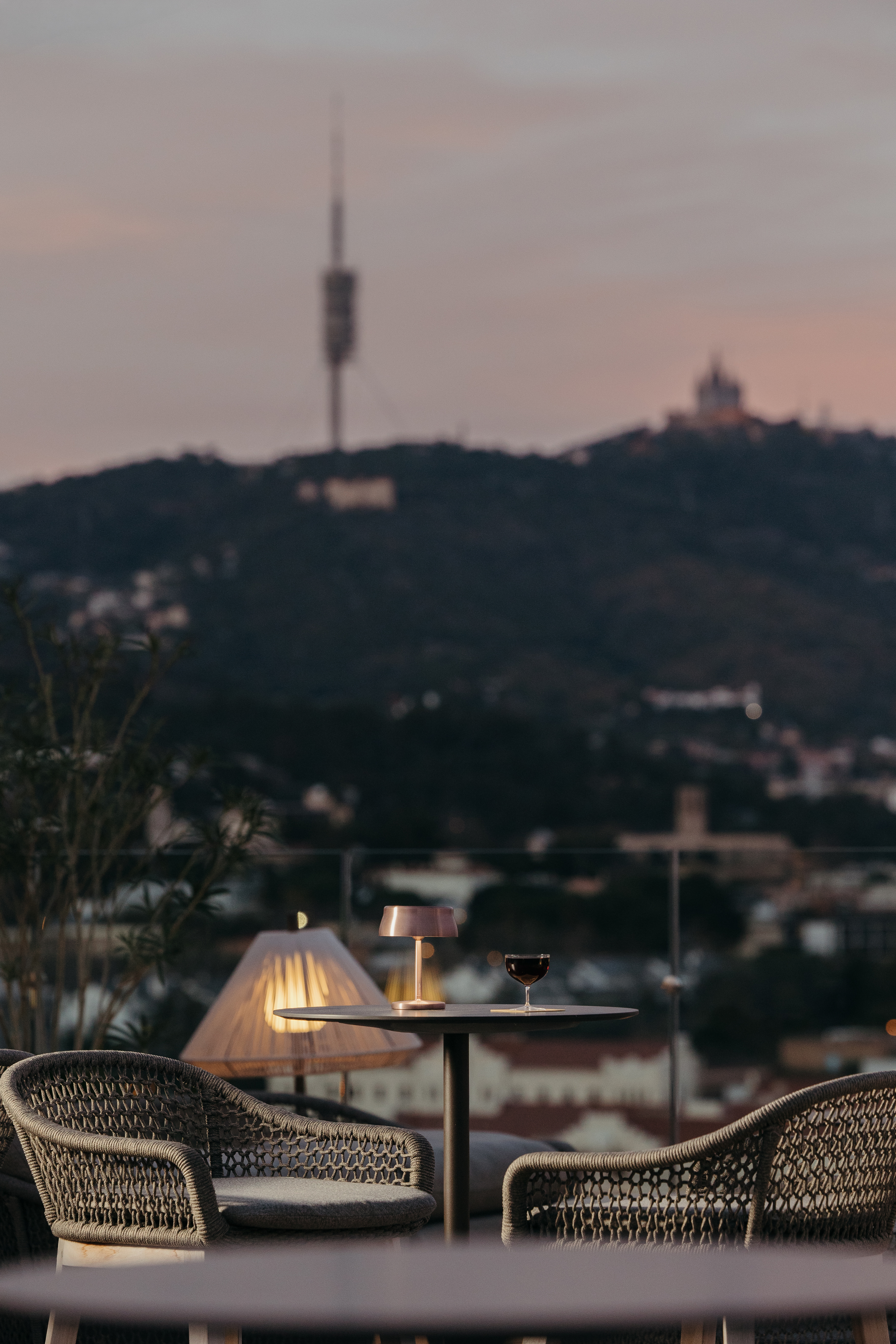 Copa de vino en terraza al atardecer con vista a la ciudad y Tibidabo.