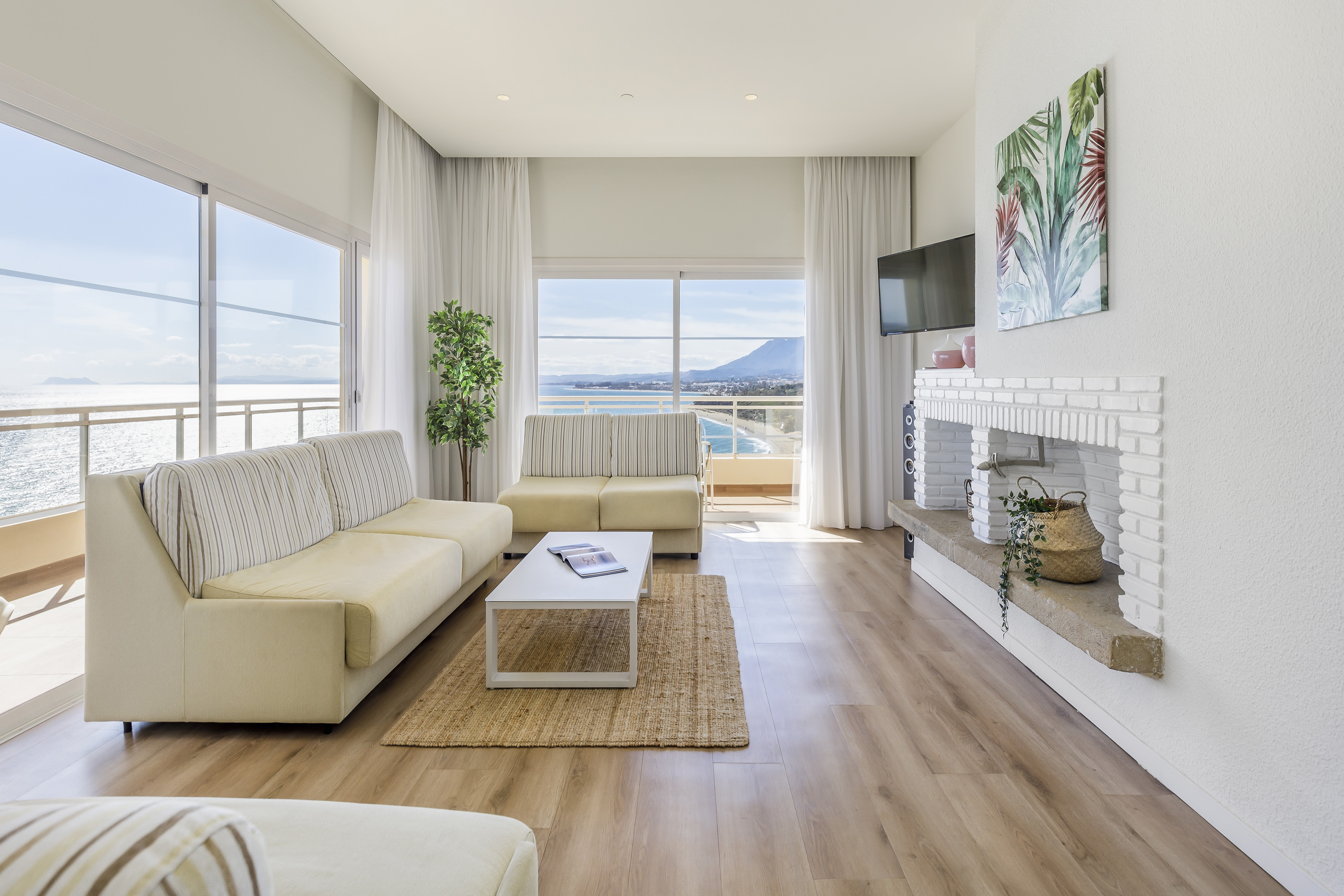 Oceanfront living room, panoramic sea views, beige sofas, modern coastal design.