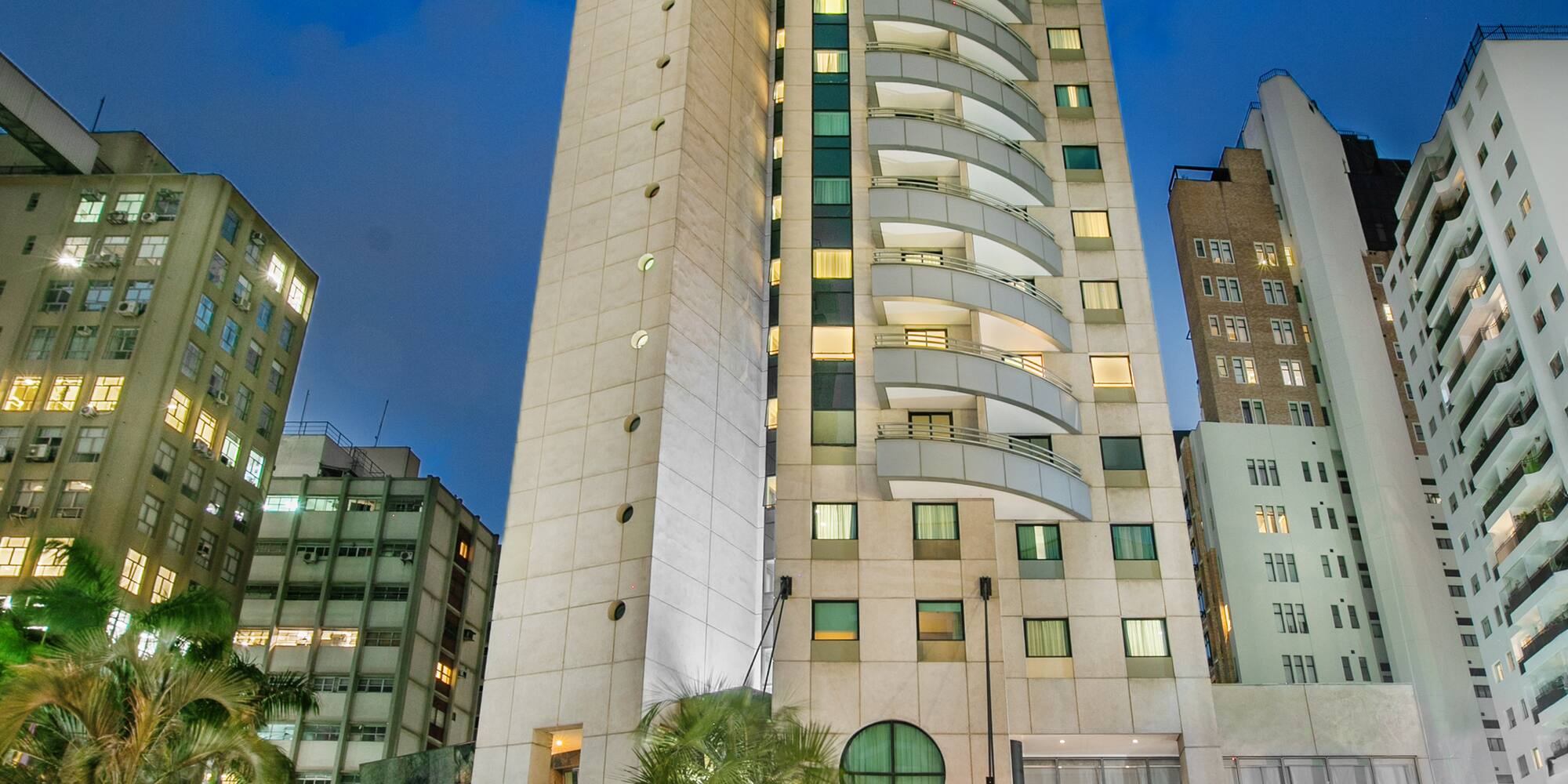Melia Jardim Europa hotel building at night with illuminated facade and palm trees.