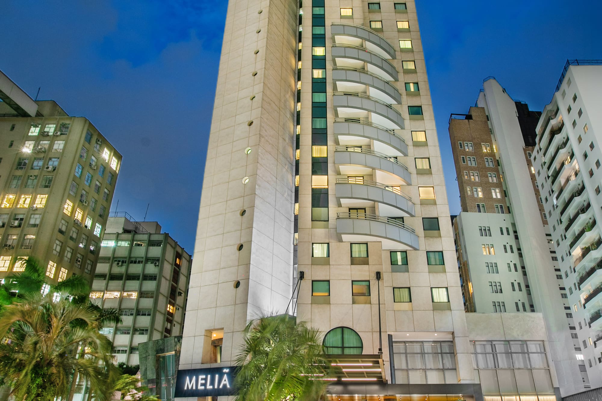 Melia Jardim Europa hotel building at night with illuminated facade and palm trees.