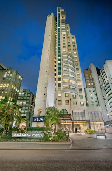 Melia Jardim Europa hotel building at night with illuminated facade and palm trees.