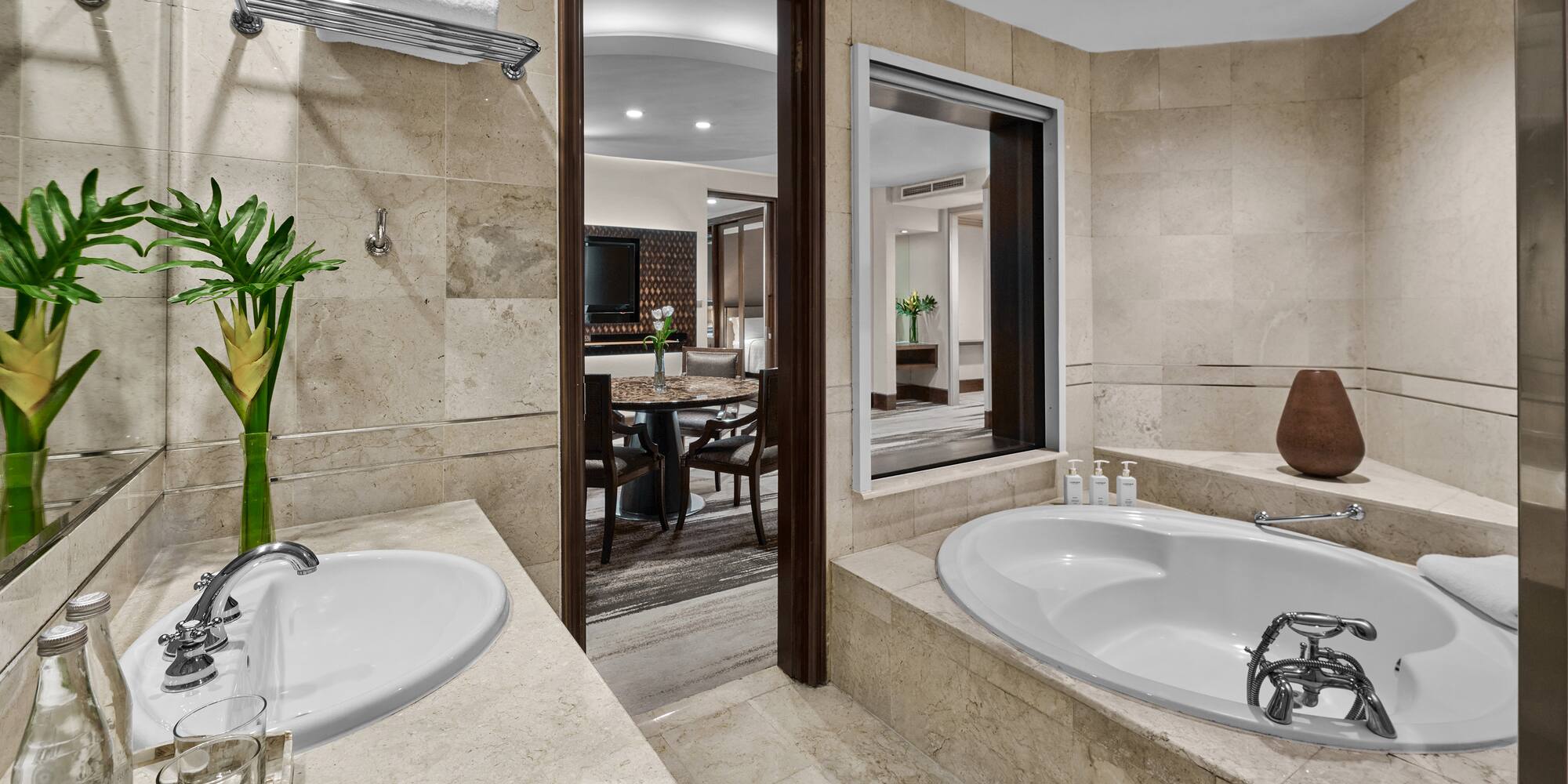 Hotel bathroom with marble vanity, double sinks, large soaking tub, and suite view.