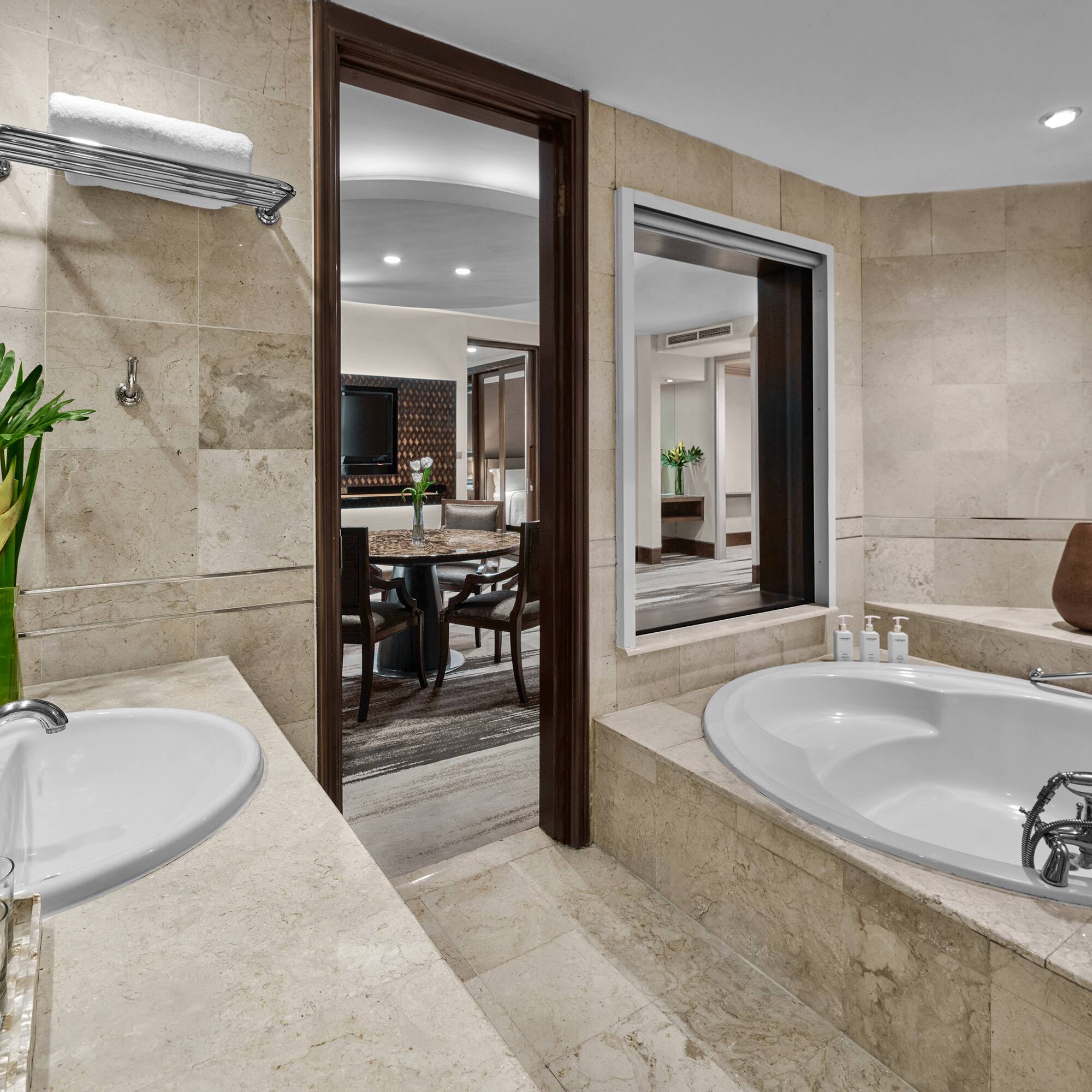 Hotel bathroom with marble vanity, double sinks, large soaking tub, and suite view.