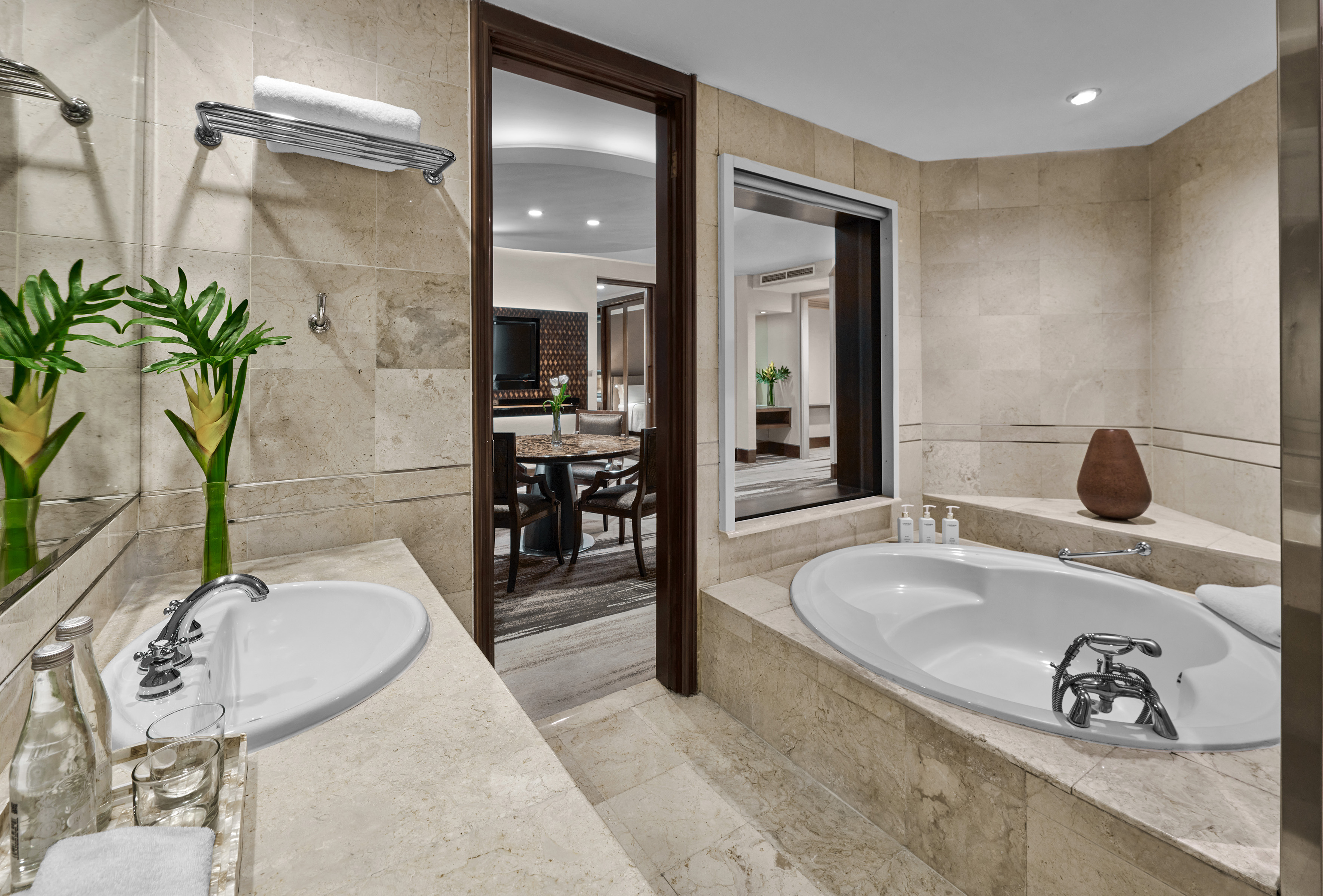 Hotel bathroom with marble vanity, double sinks, large soaking tub, and suite view.
