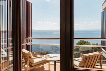 a balcony with chairs and a table overlooking the ocean
