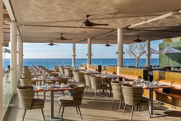 a restaurant with tables and chairs and a large body of water