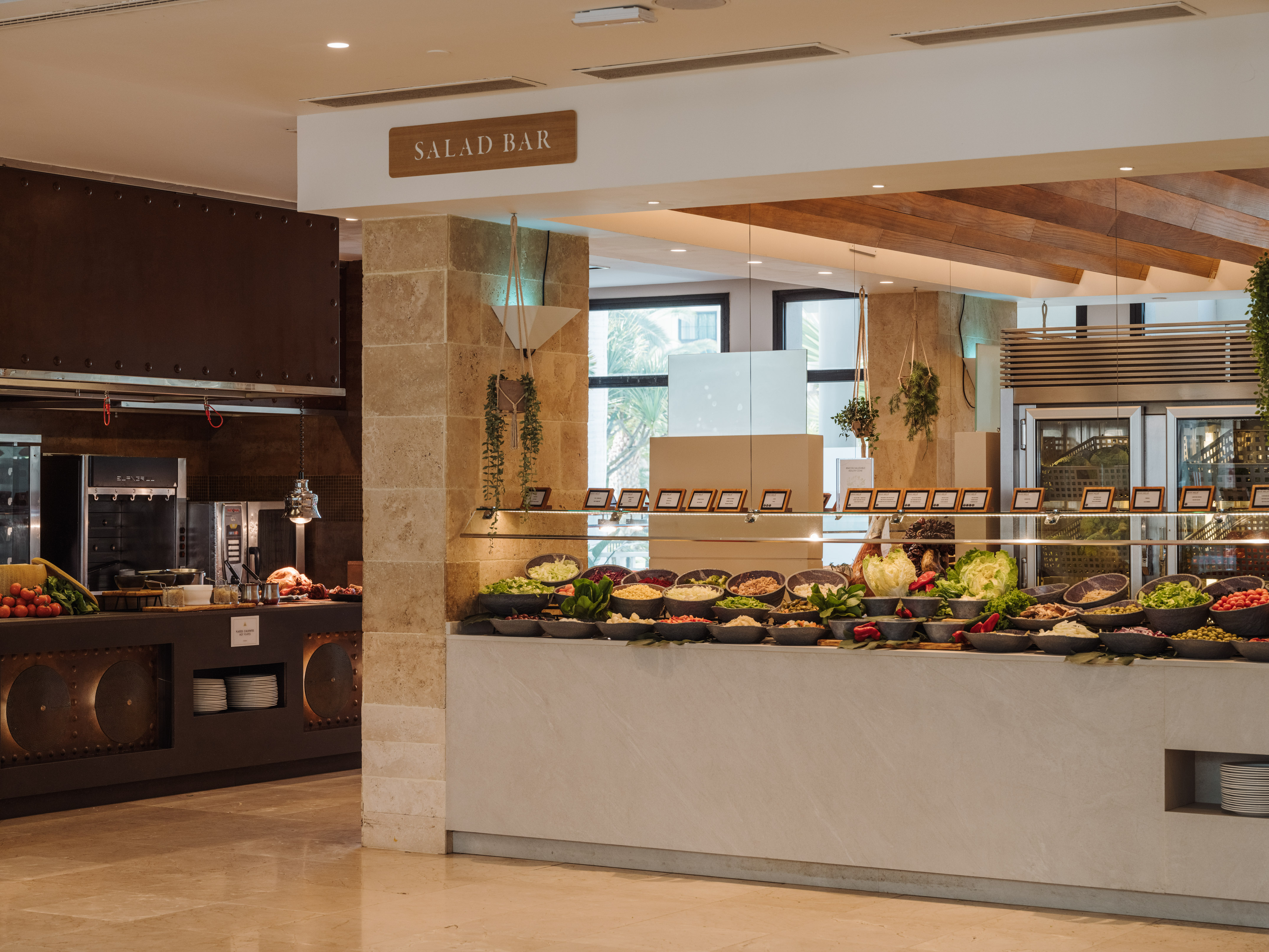 Modern hotel salad bar buffet with fresh vegetables and hot food station.