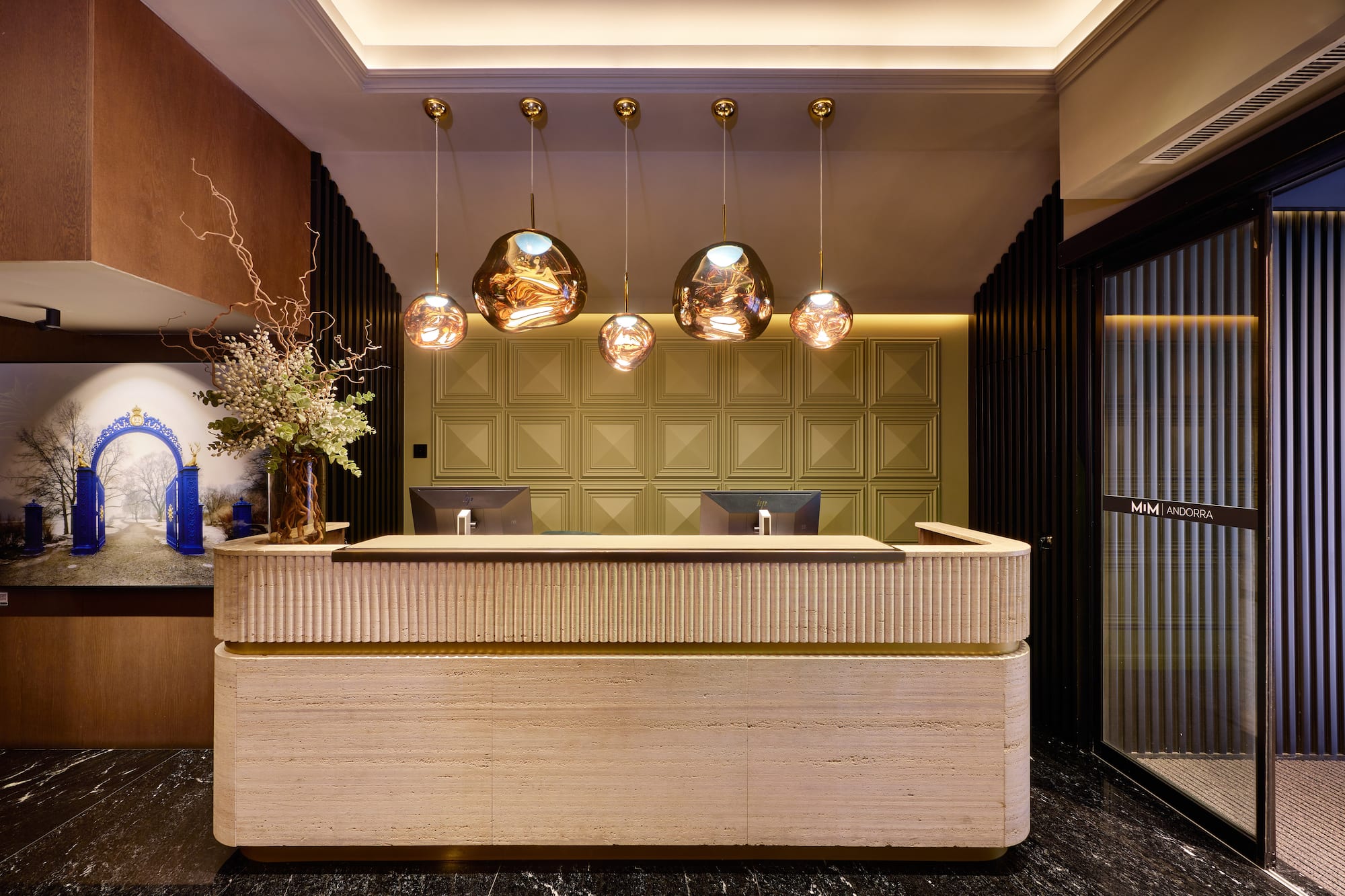 MiM Andorra hotel reception with ribbed desk, modern pendant lights, and green wall.