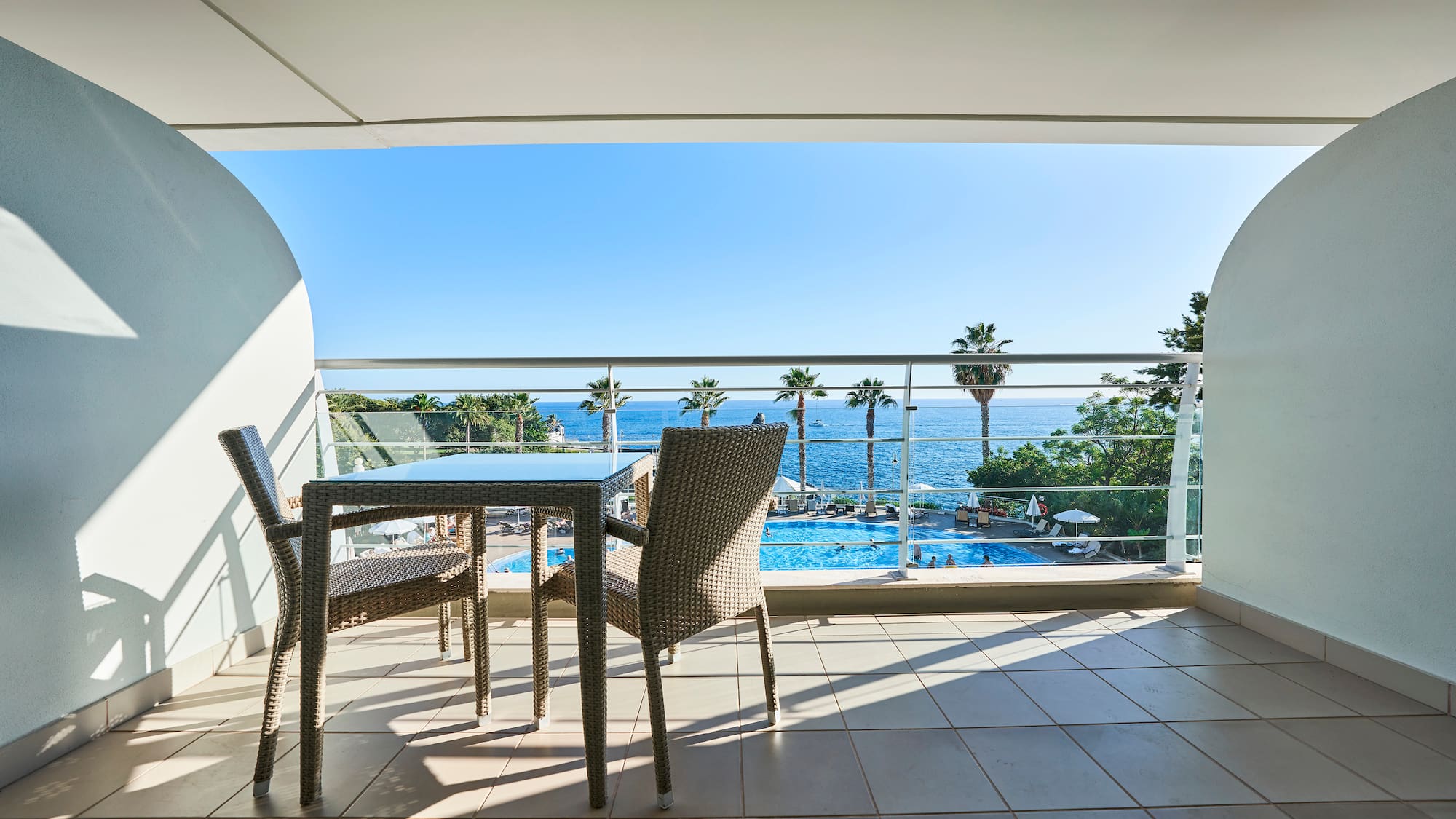 a table and chairs on a balcony overlooking a pool