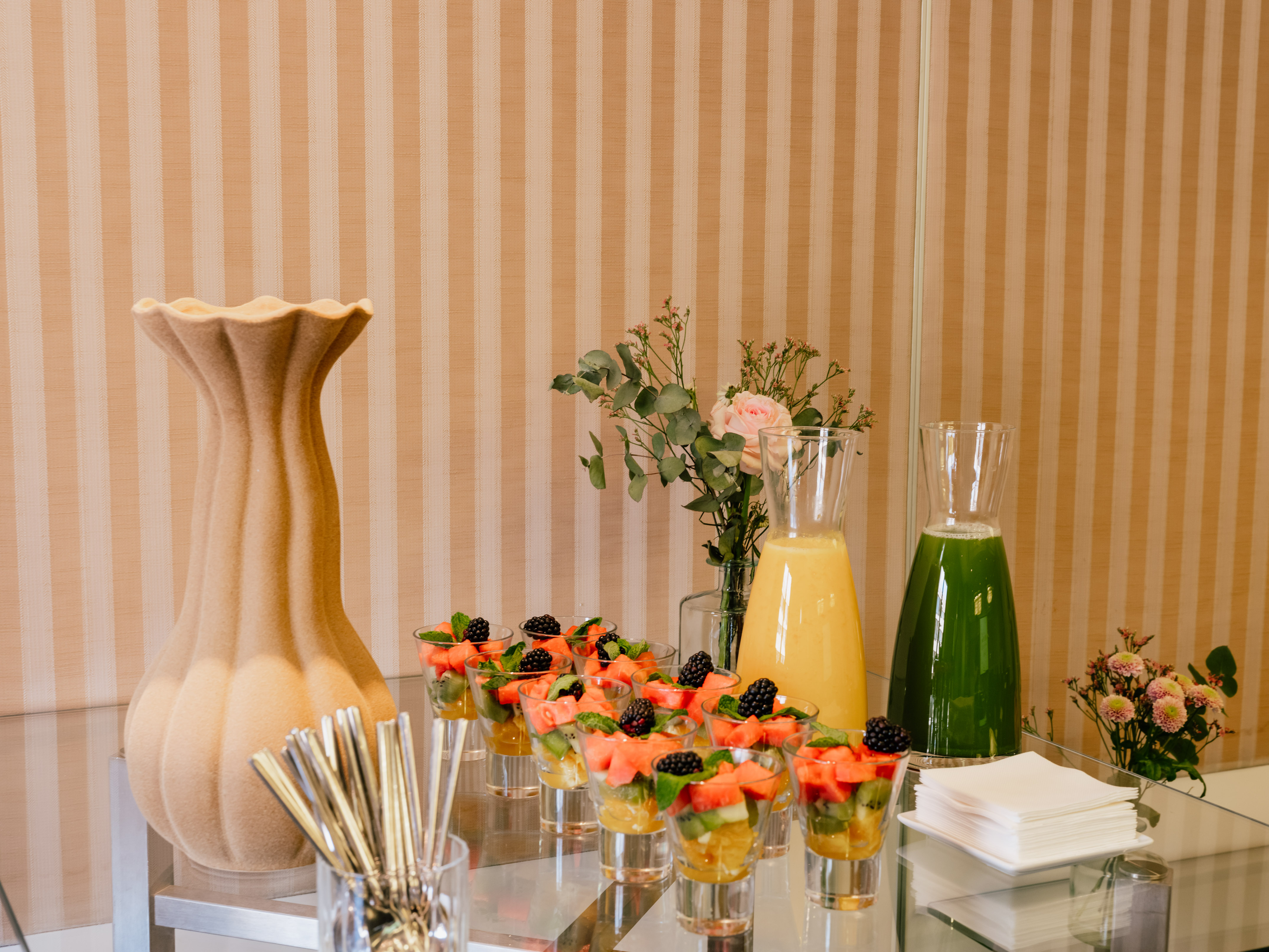 Fresh fruit cups and assorted juices on an elegant breakfast buffet table.