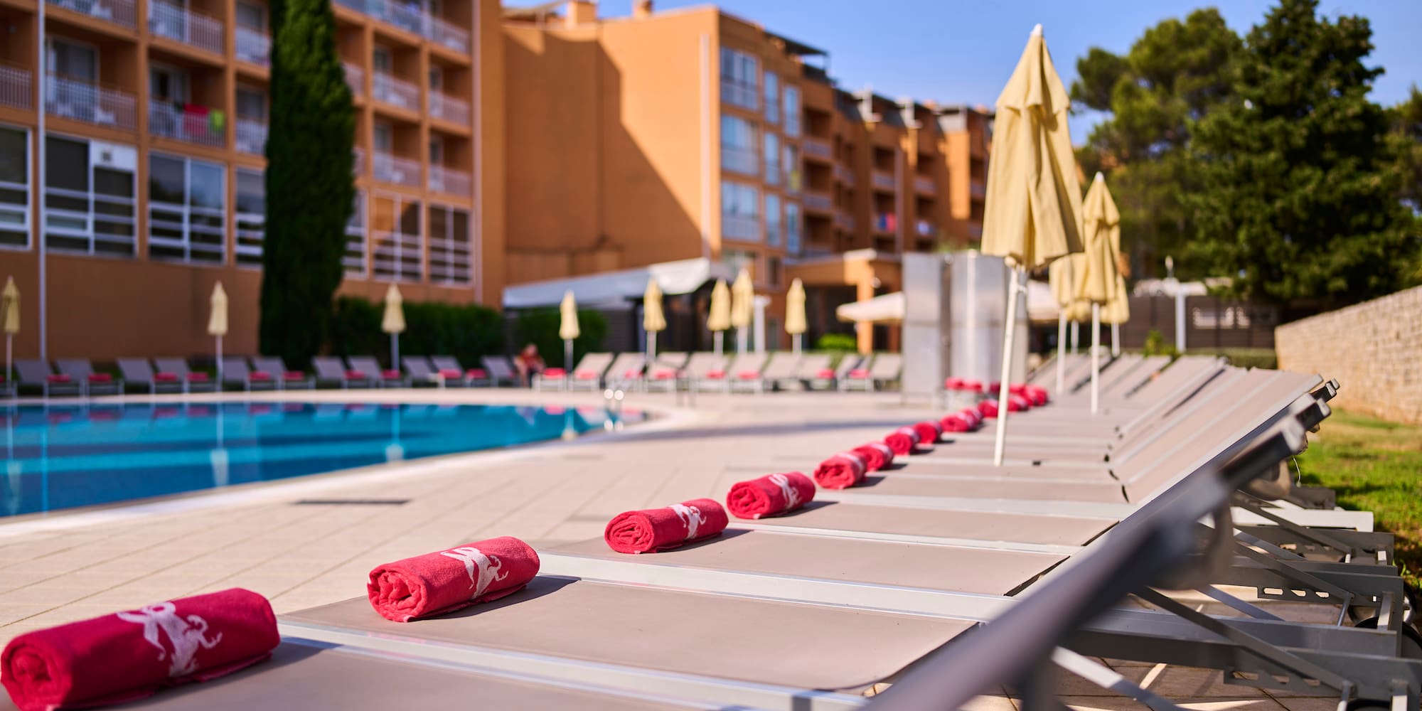 a pool with red towels and umbrellas