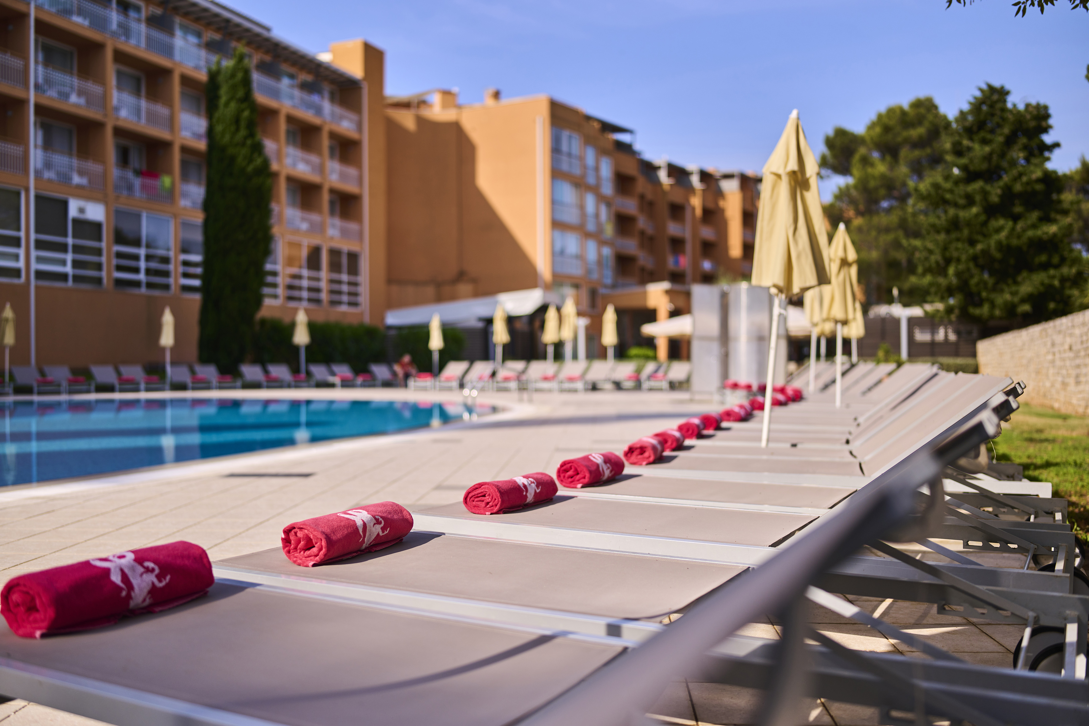 a pool with red towels and umbrellas