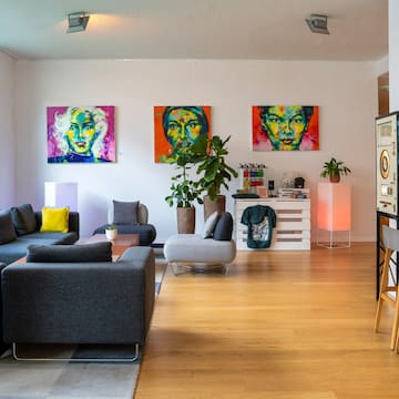 a living room with couches and paintings on the wall