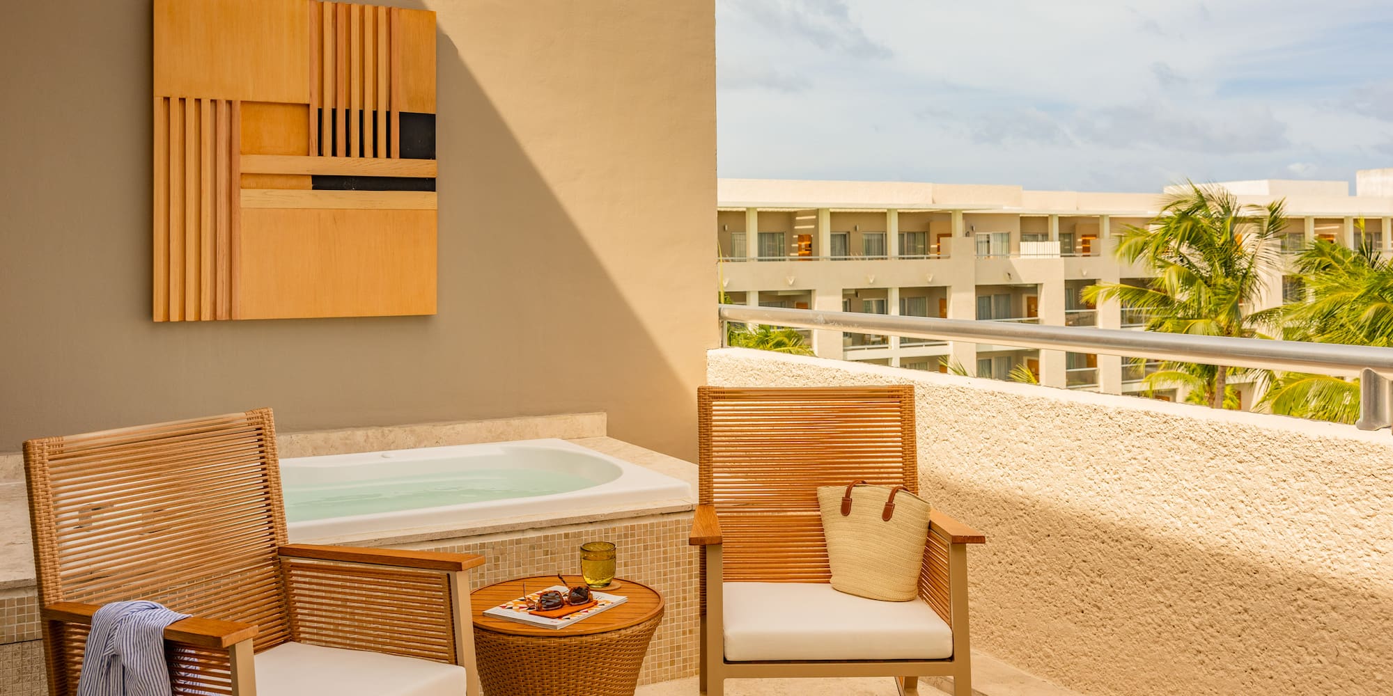 Private hotel terrace with outdoor hot tub, chairs, and tropical resort view.