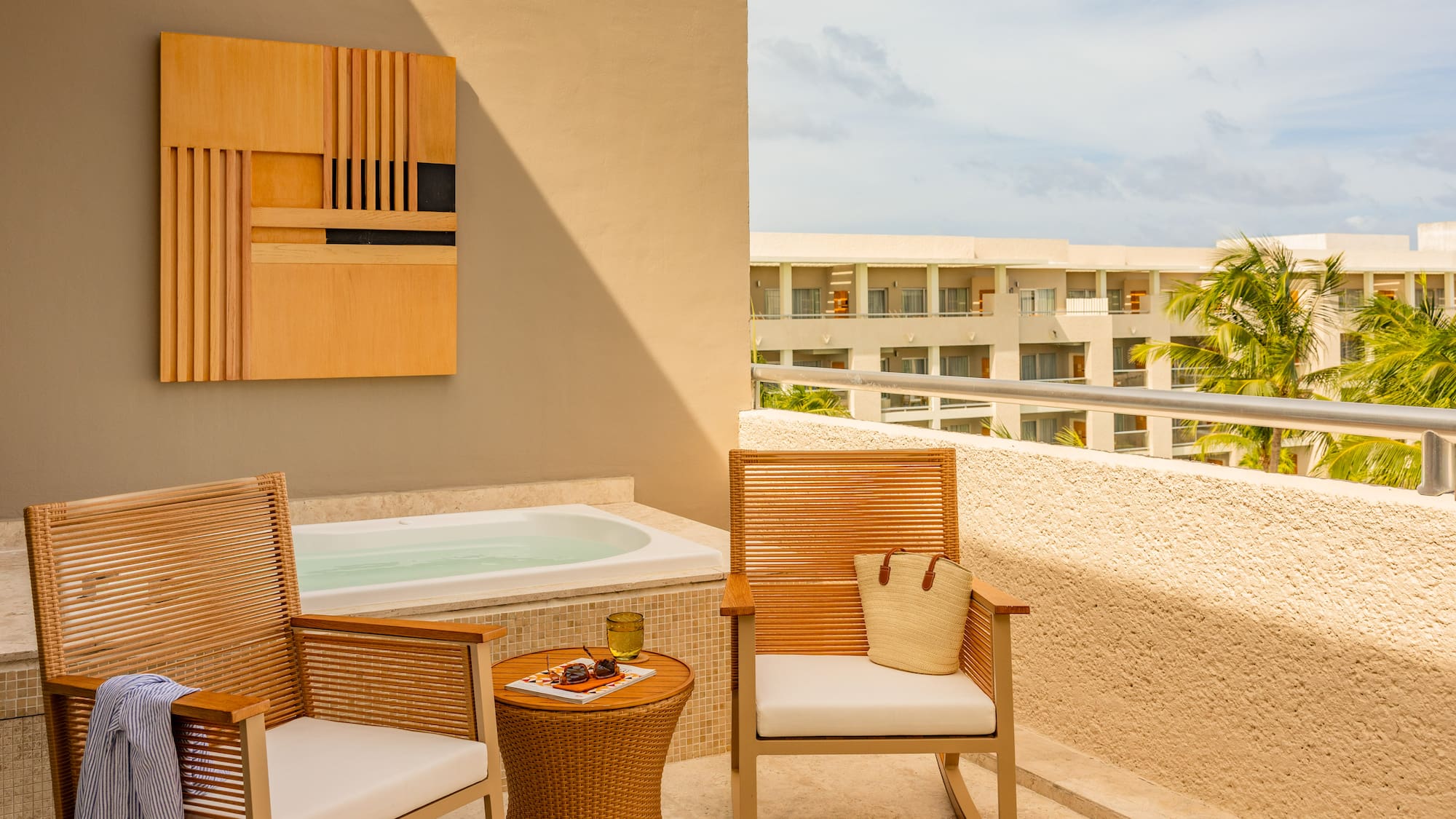 Private hotel terrace with outdoor hot tub, chairs, and tropical resort view.