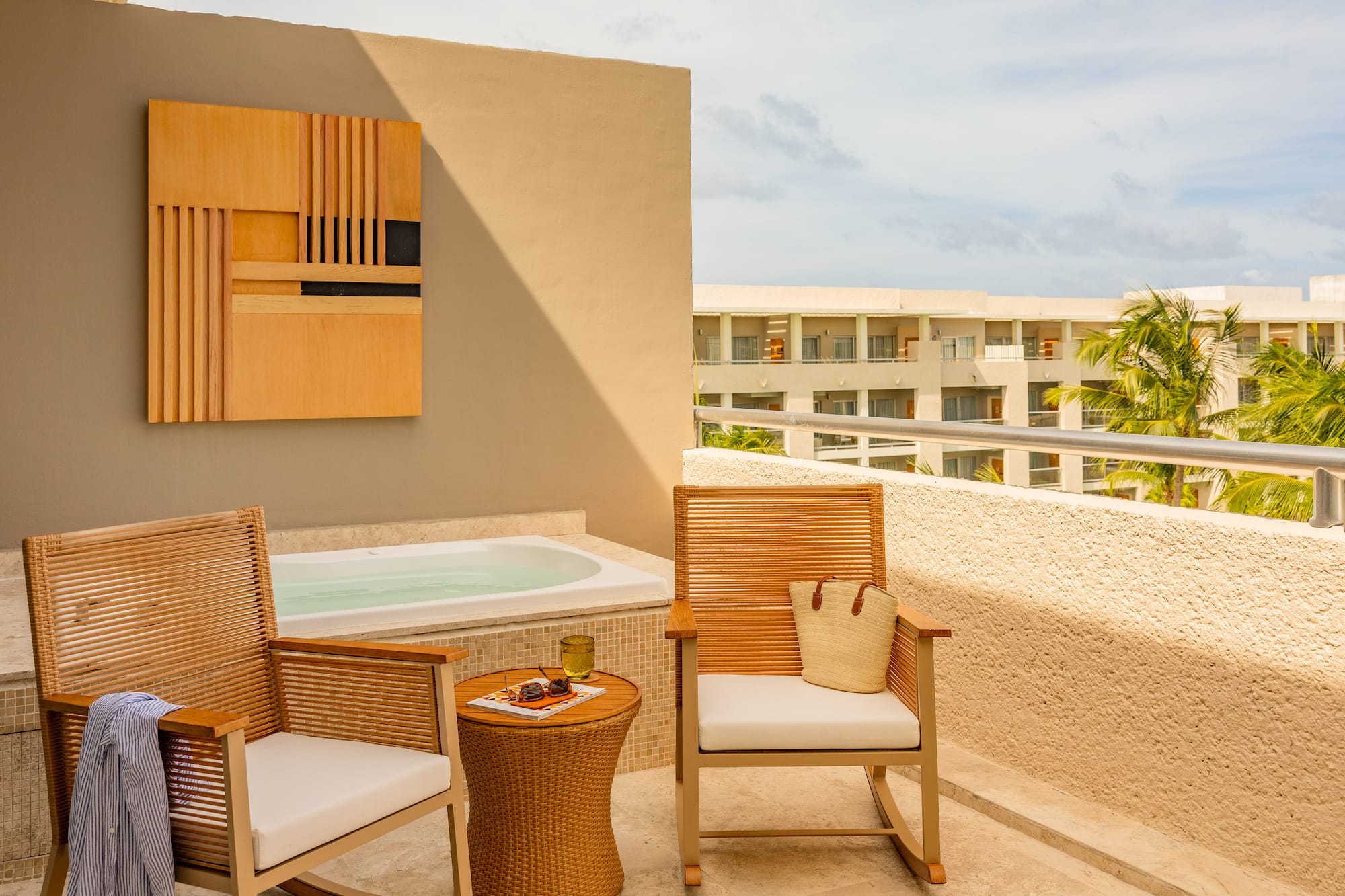 Private hotel terrace with outdoor hot tub, chairs, and tropical resort view.