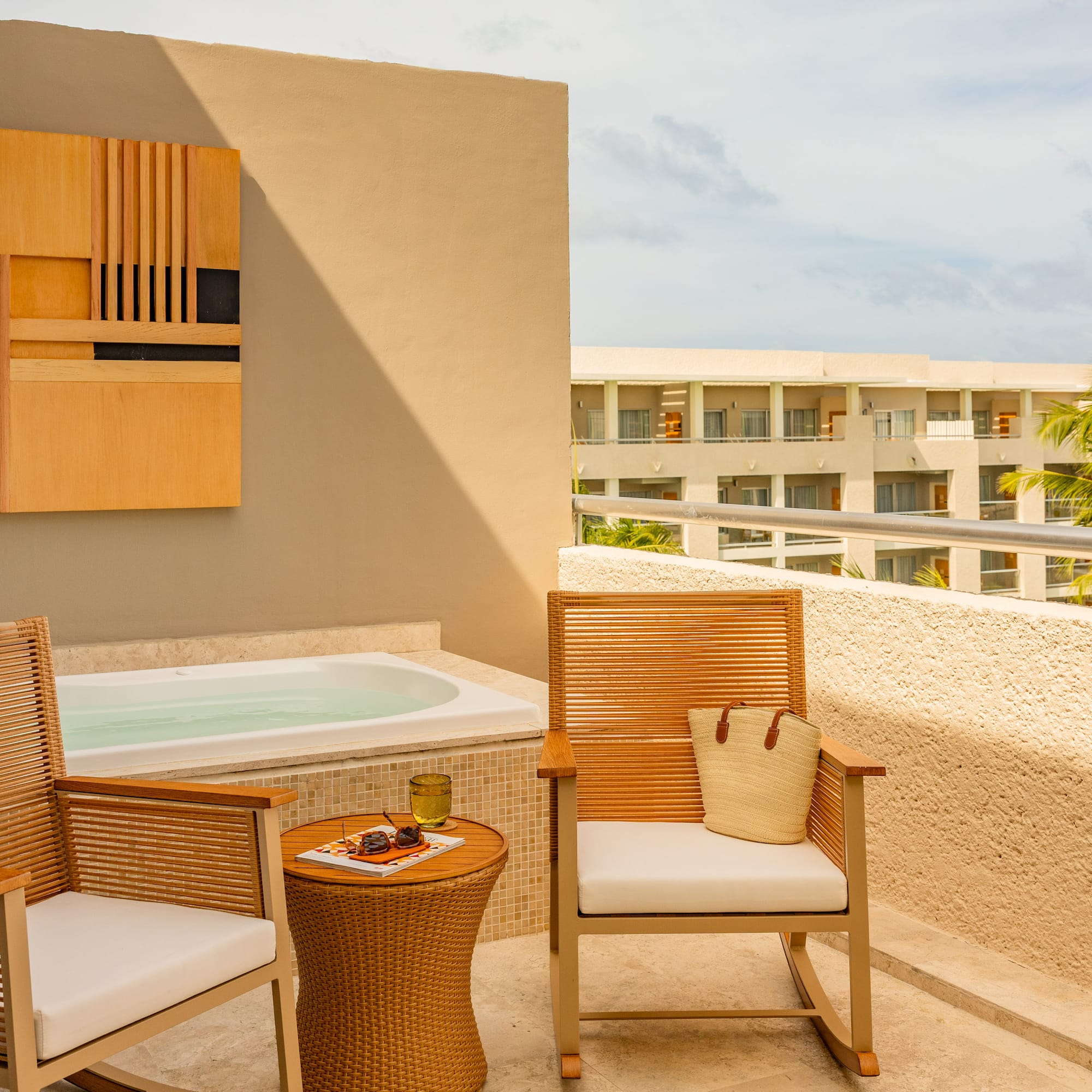 Private hotel terrace with outdoor hot tub, chairs, and tropical resort view.