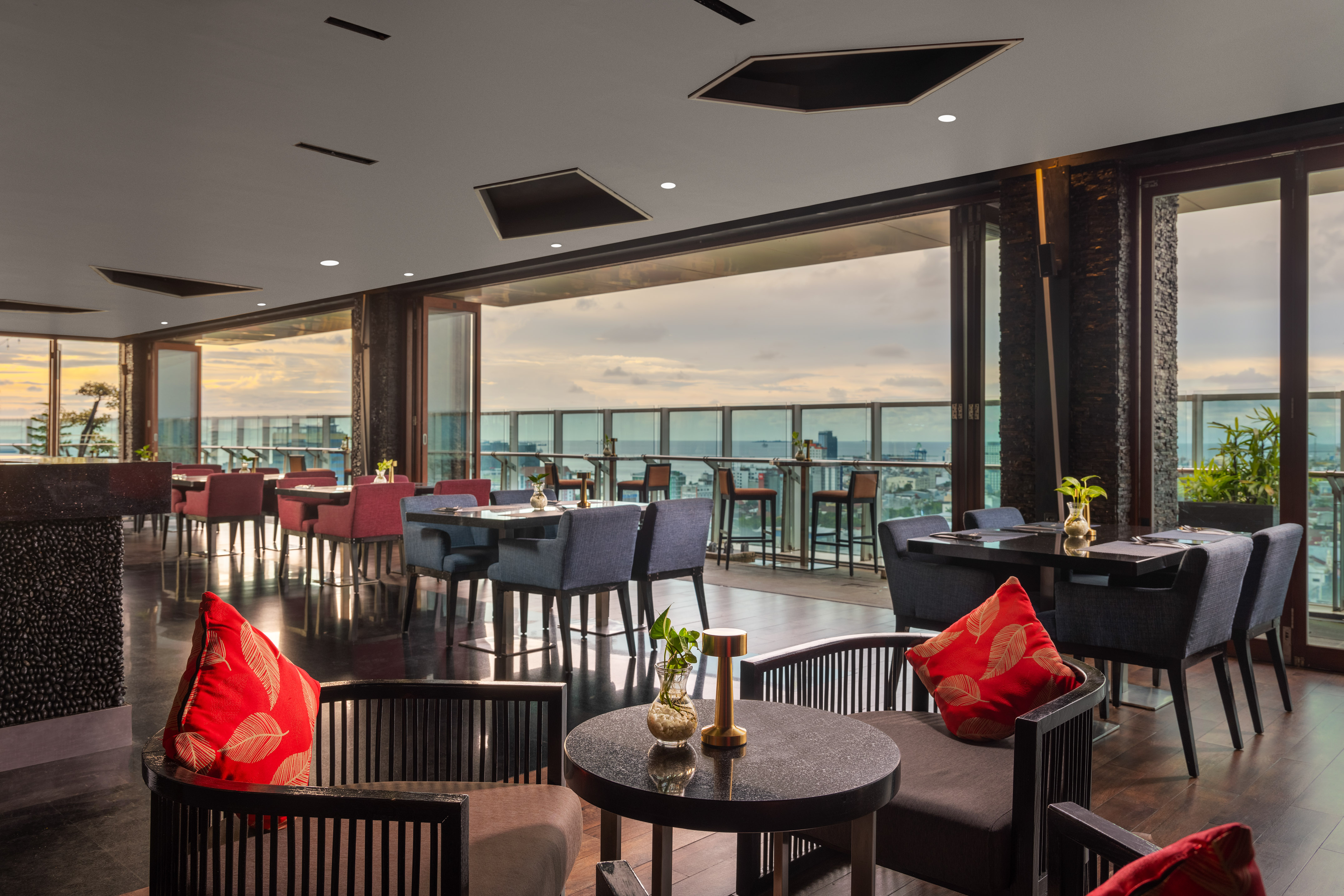 Modern rooftop restaurant lounge, city view, elegant seating, red accents.