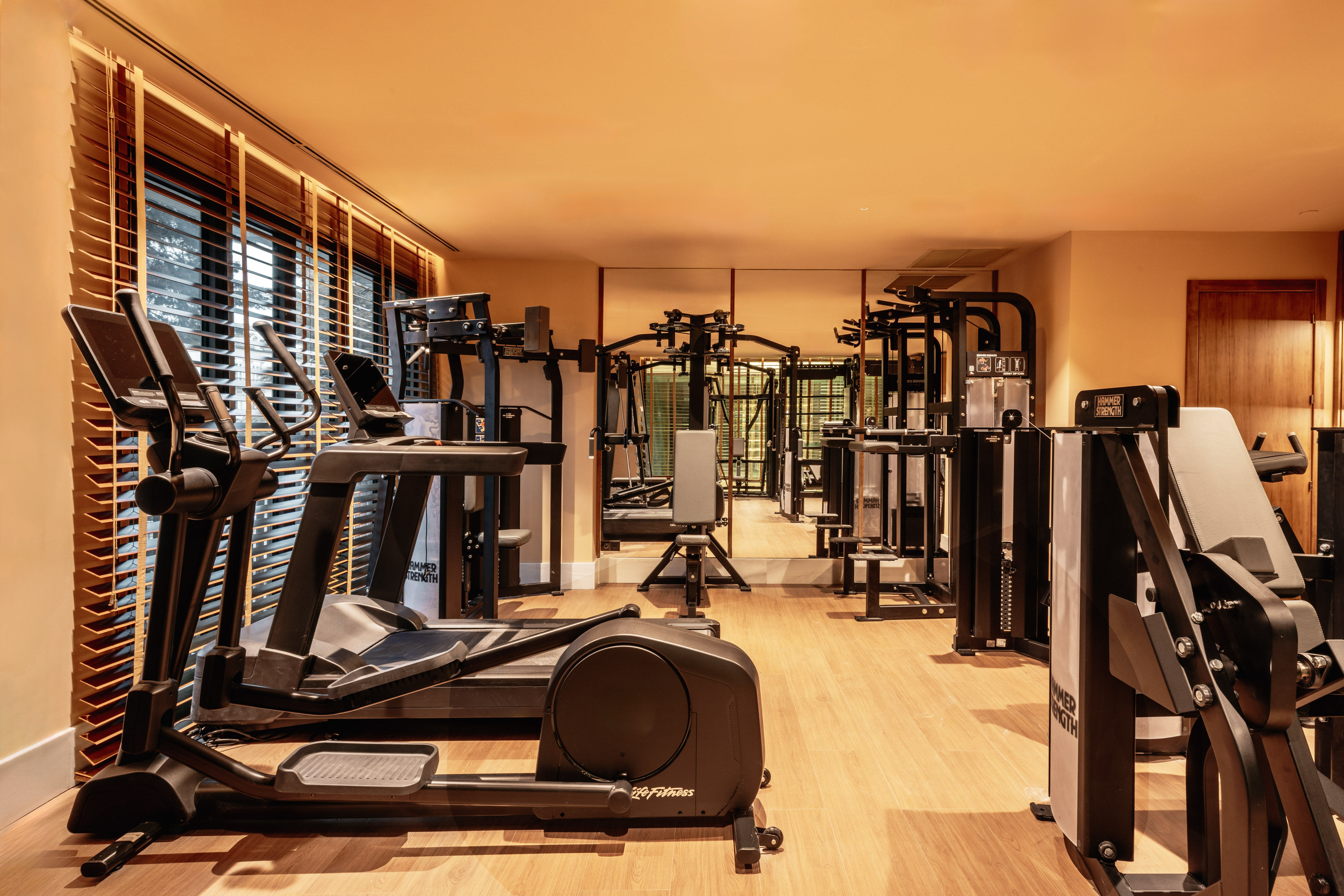 Modern fitness center with elliptical, weight machines, and warm lighting.