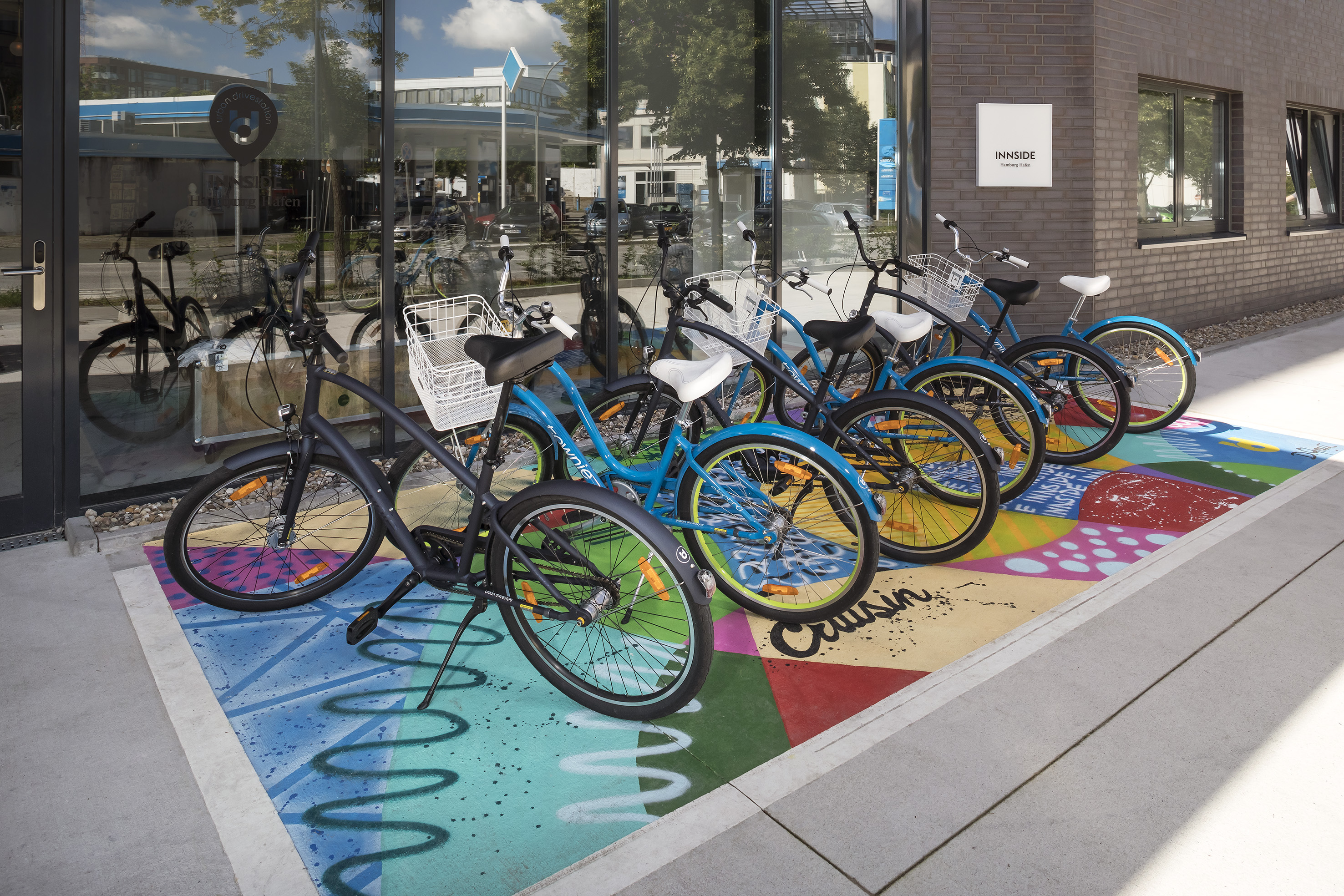 Blue and black bikes on colorful ground outside INNSIDE Hamburg Hafen.