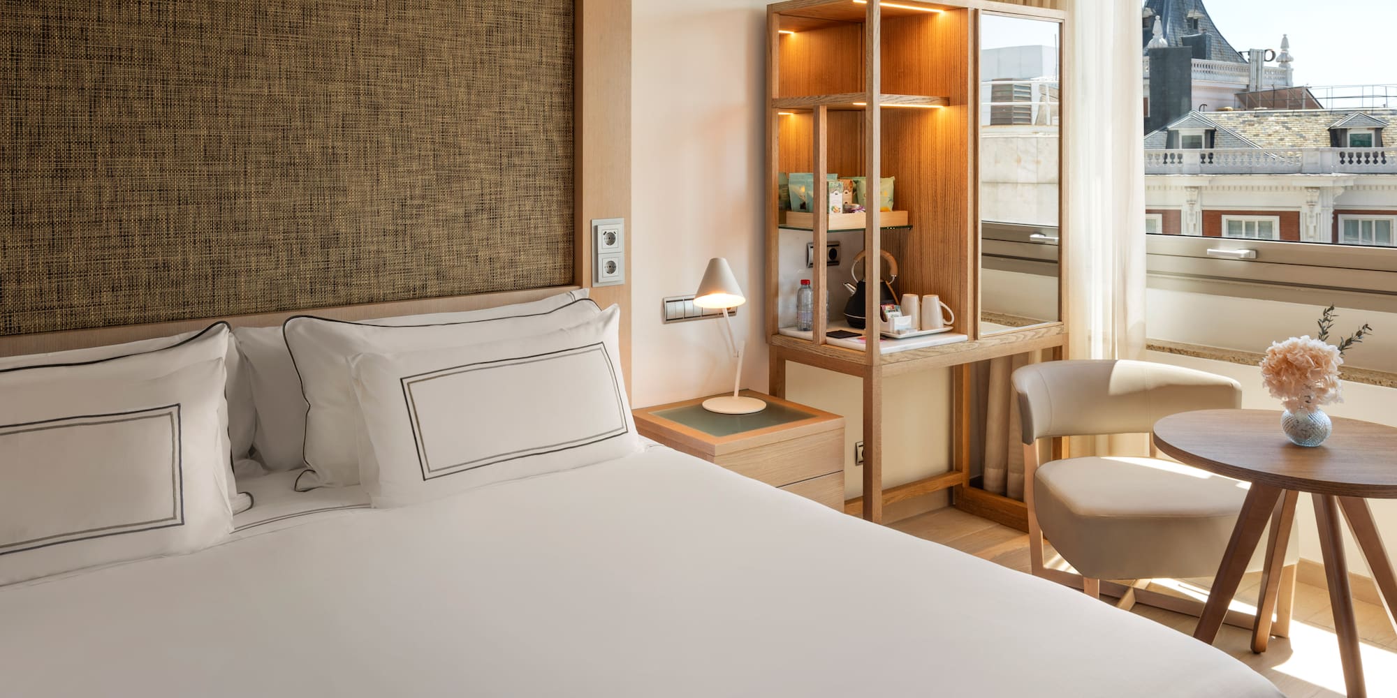 a bed with a white cover and a chair in a room with a window