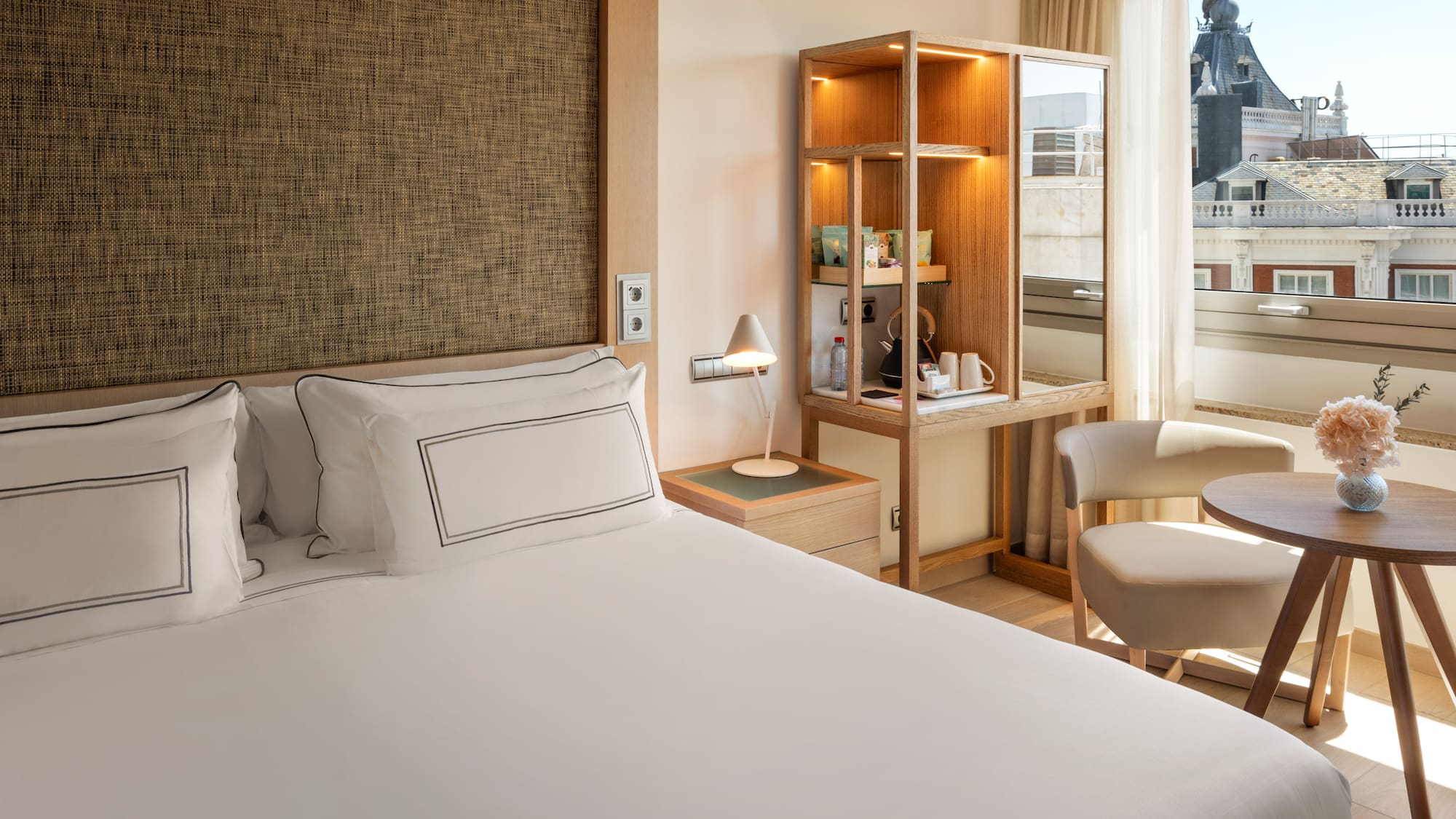 a bed with a white cover and a chair in a room with a window