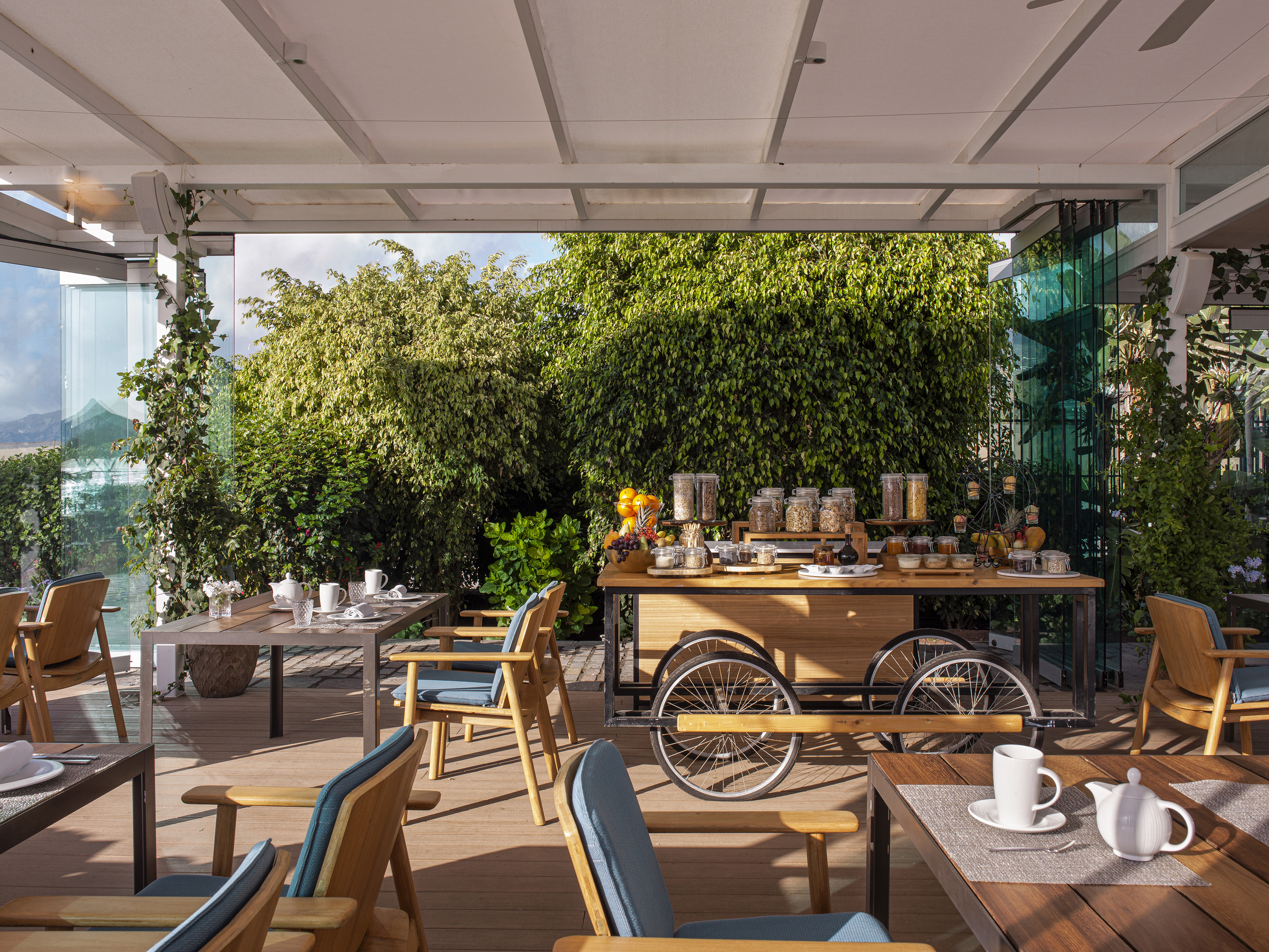 Al fresco breakfast buffet on patio with cereals, fruits, and garden.