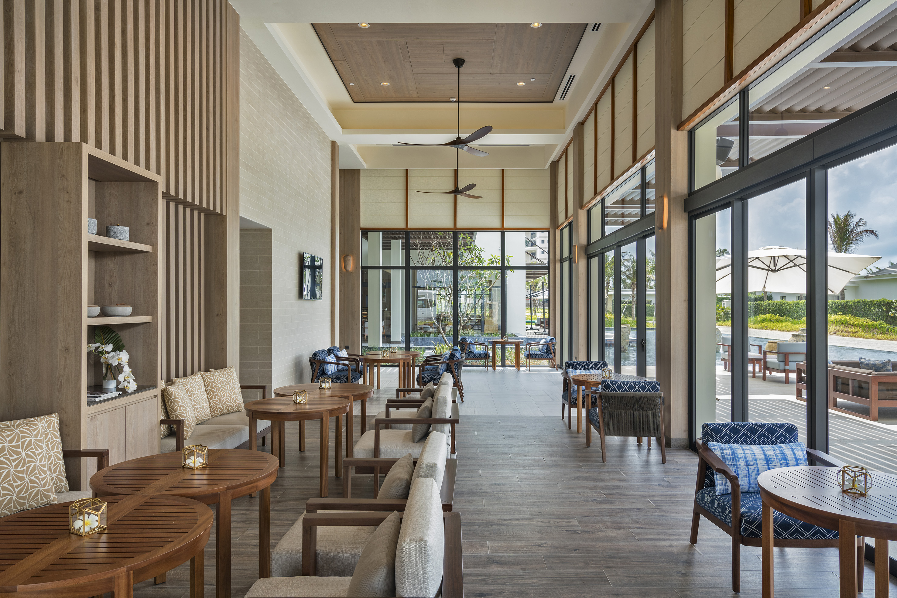 Modern resort lounge with wood details, blue seating, and scenic outdoor views.