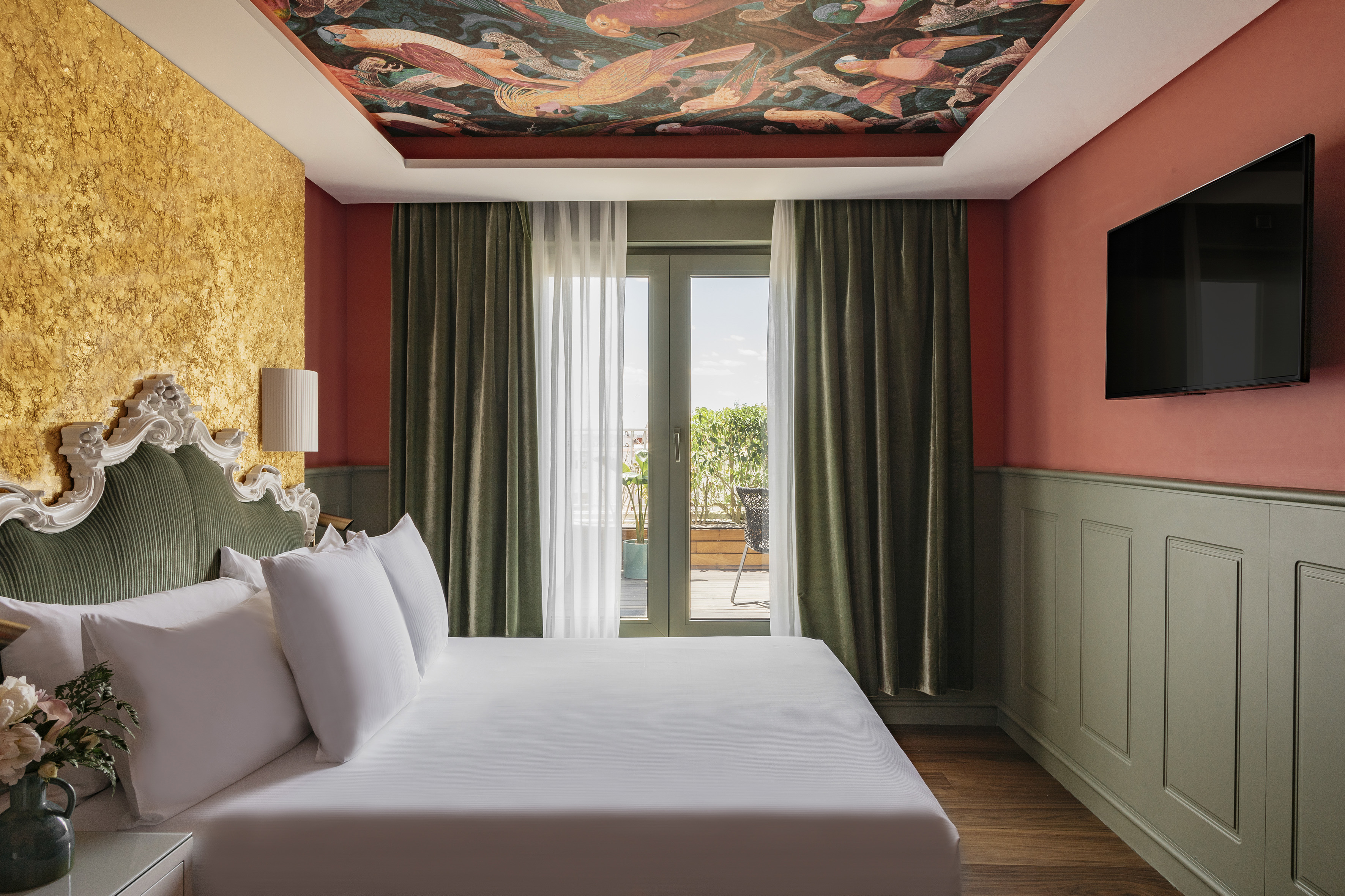 Ornate luxury bedroom with colorful ceiling, golden wall, and balcony.