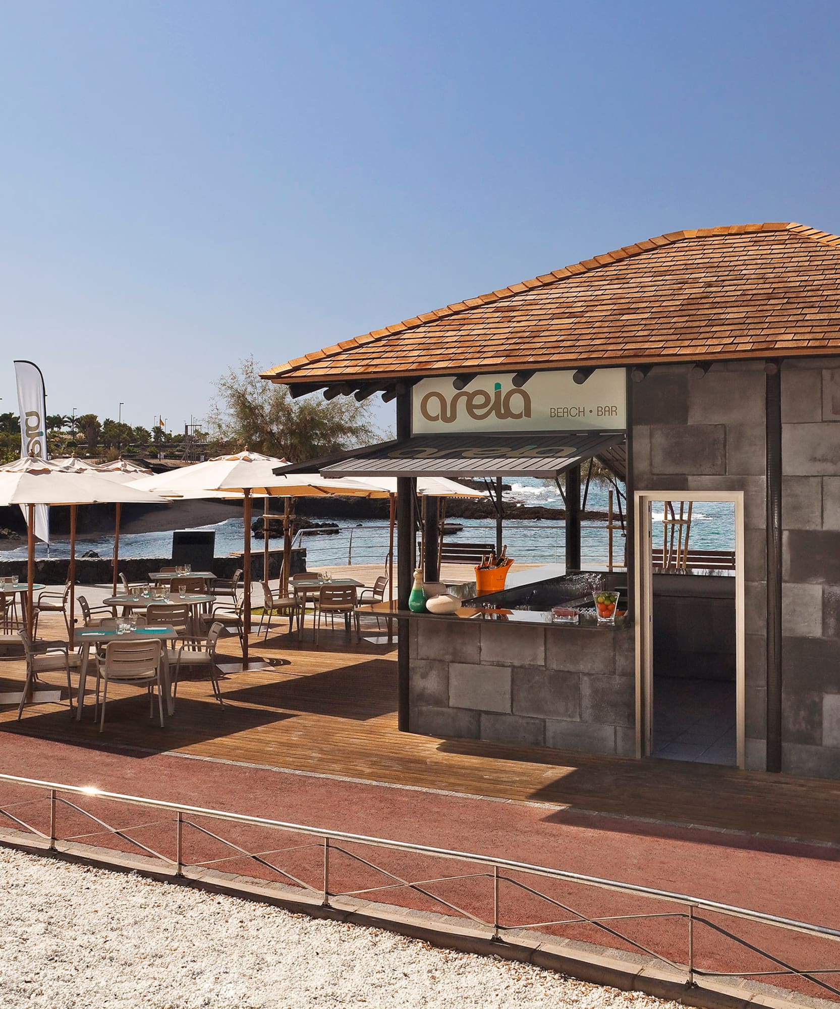Areia Beach Bar outdoor patio with tables, umbrellas, and ocean view.