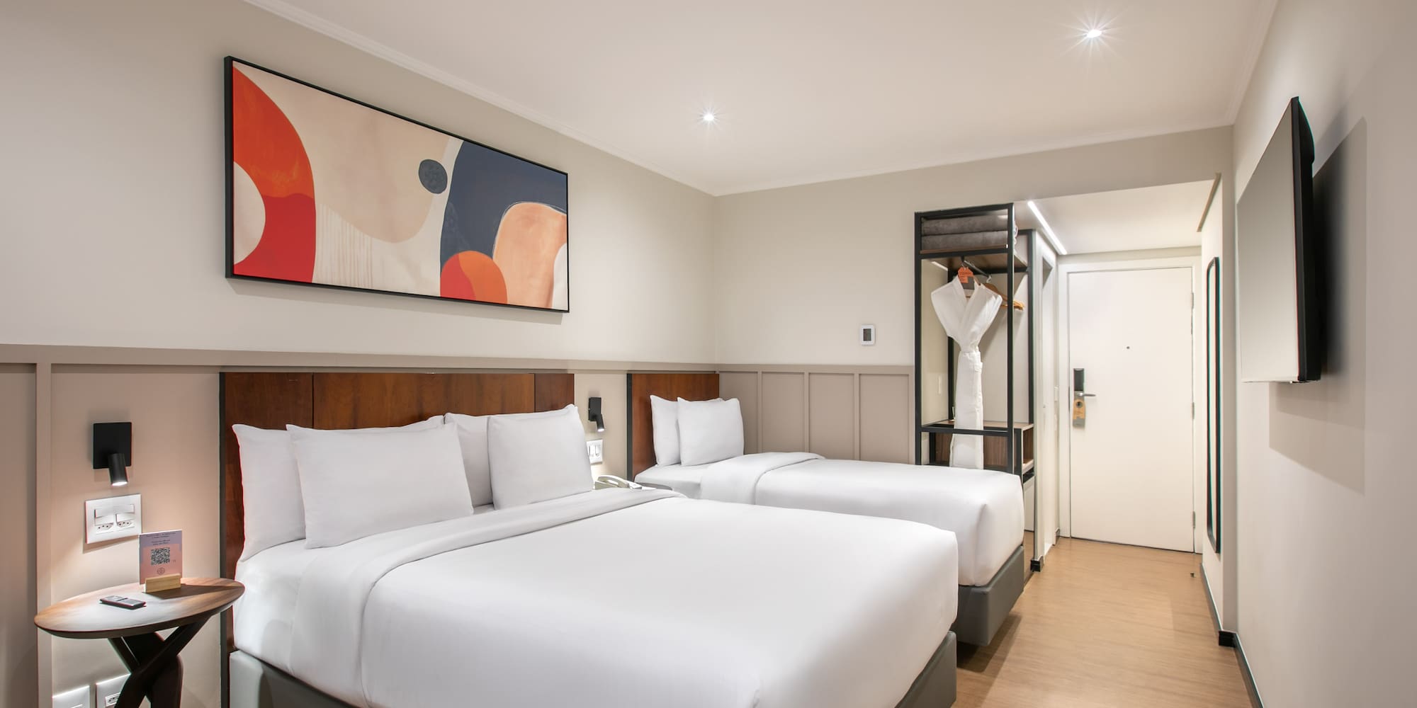 Modern hotel room with two comfortable beds, abstract art, and stylish decor.