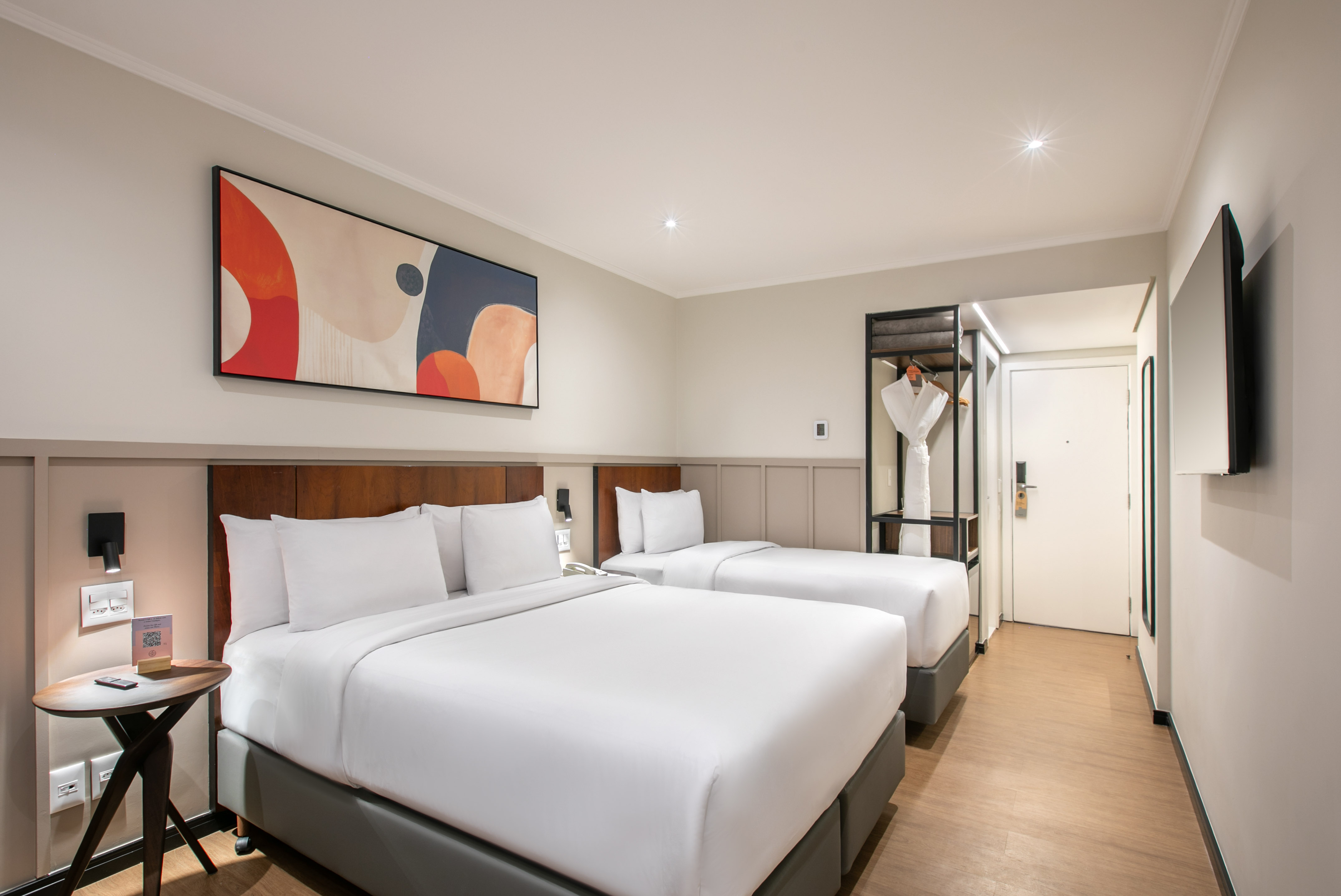 Modern hotel room with two comfortable beds, abstract art, and stylish decor.