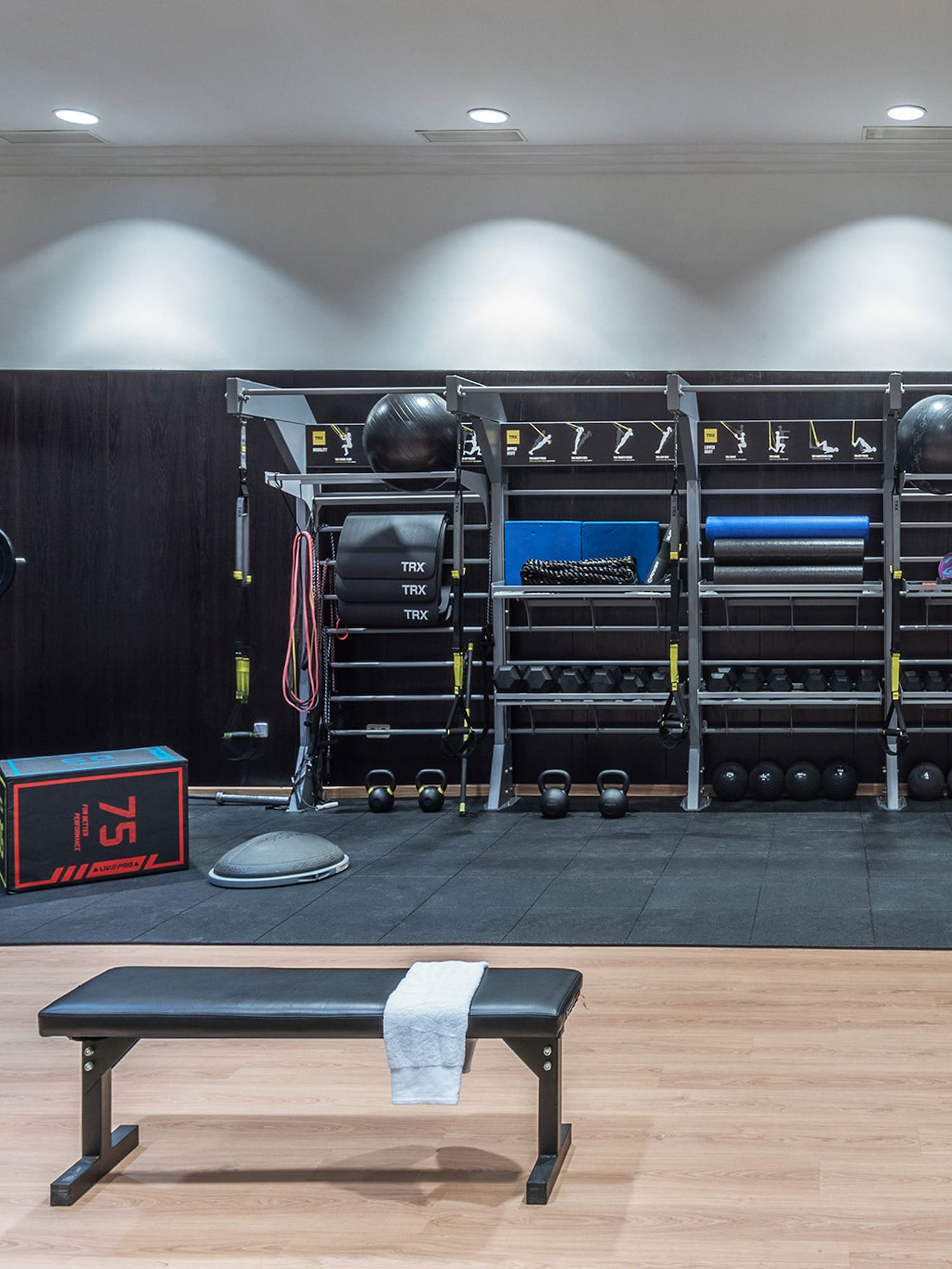 Clean gym with weight rack, kettlebells, dumbbells, and functional training equipment.