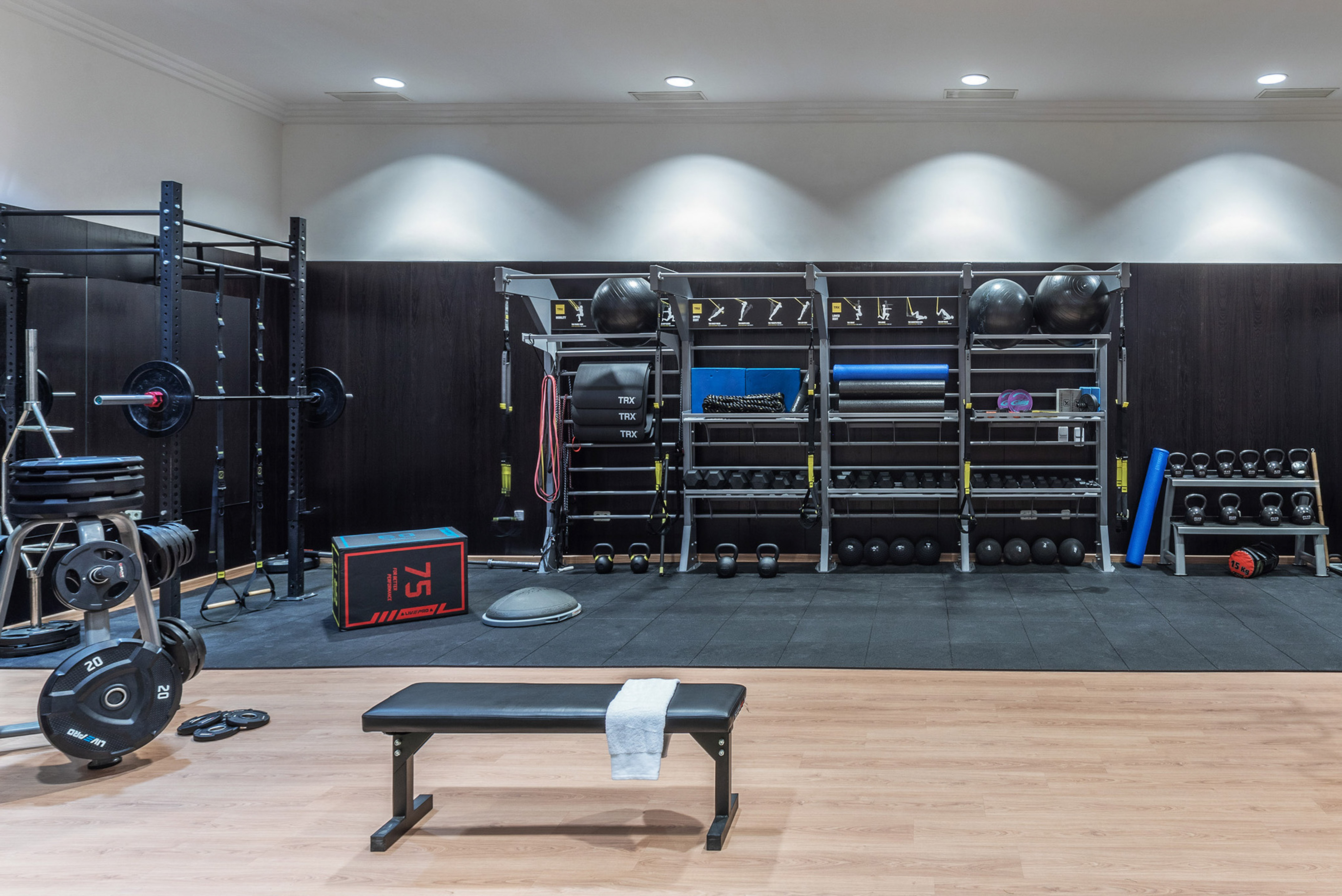 Clean gym with weight rack, kettlebells, dumbbells, and functional training equipment.