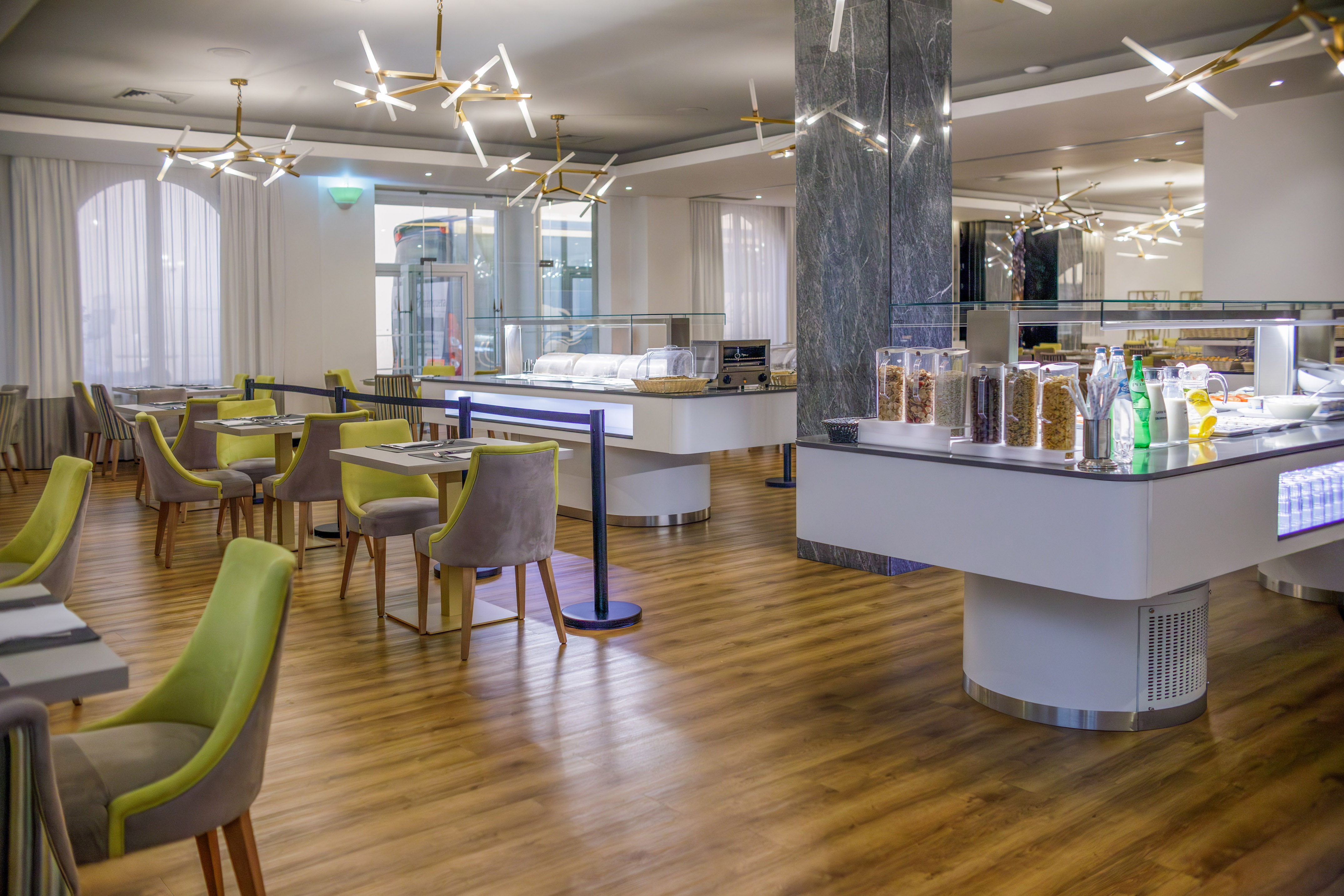 Modern hotel dining room, breakfast buffet, lime green chairs, and stylish lighting.