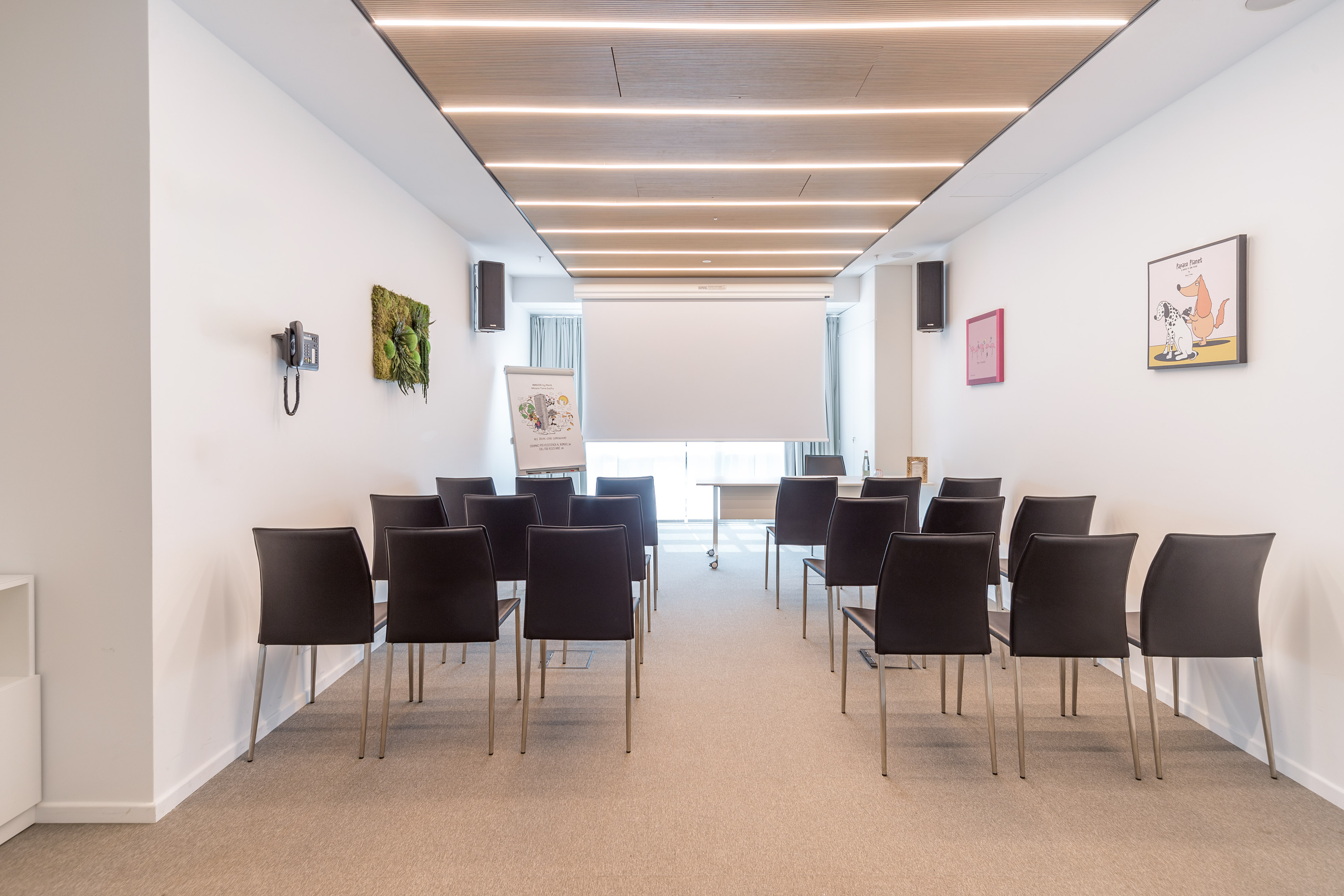 Modern training room with theater seating, projection screen, and flip chart.