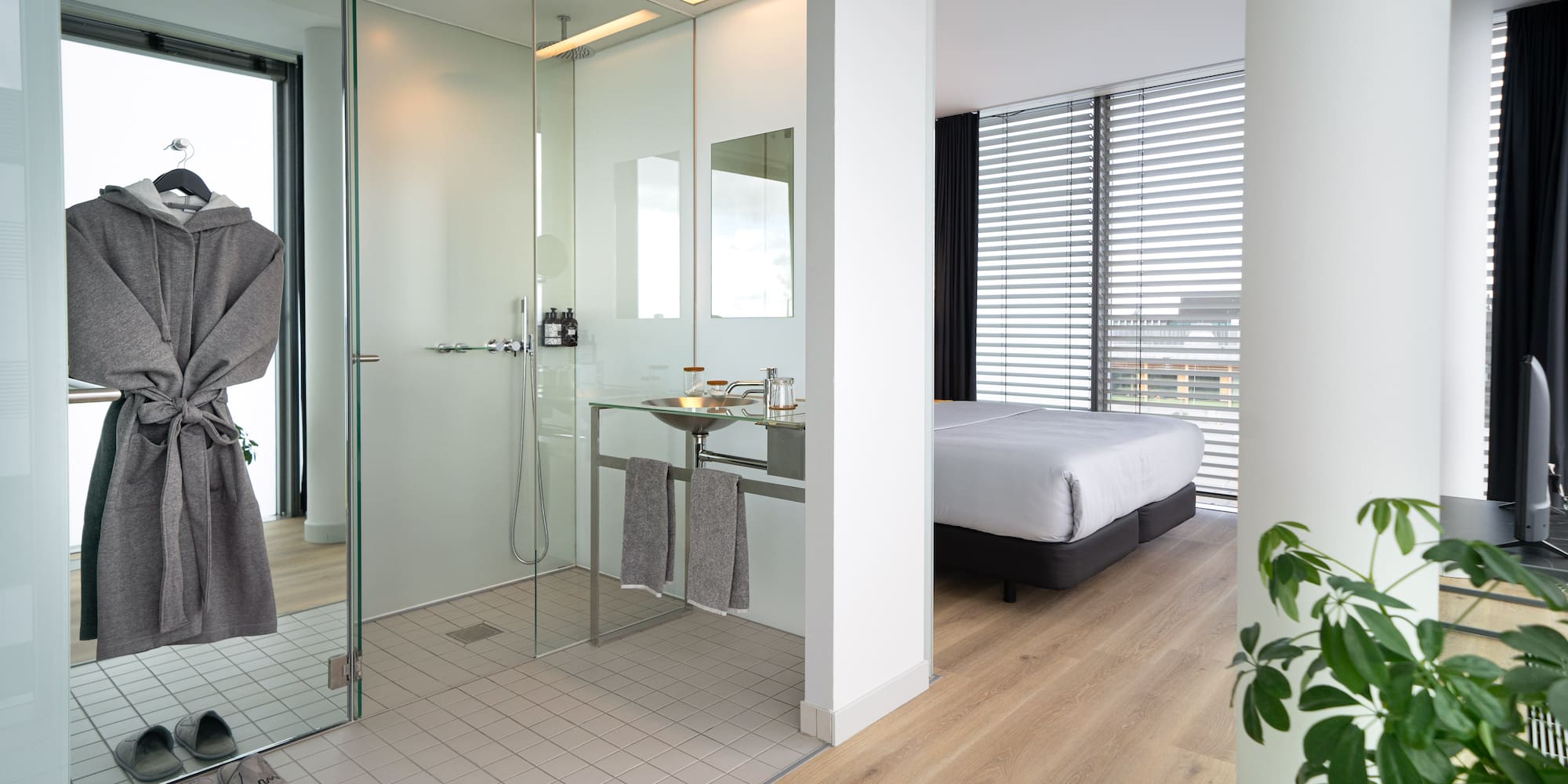 a bathroom with a glass shower and a bed