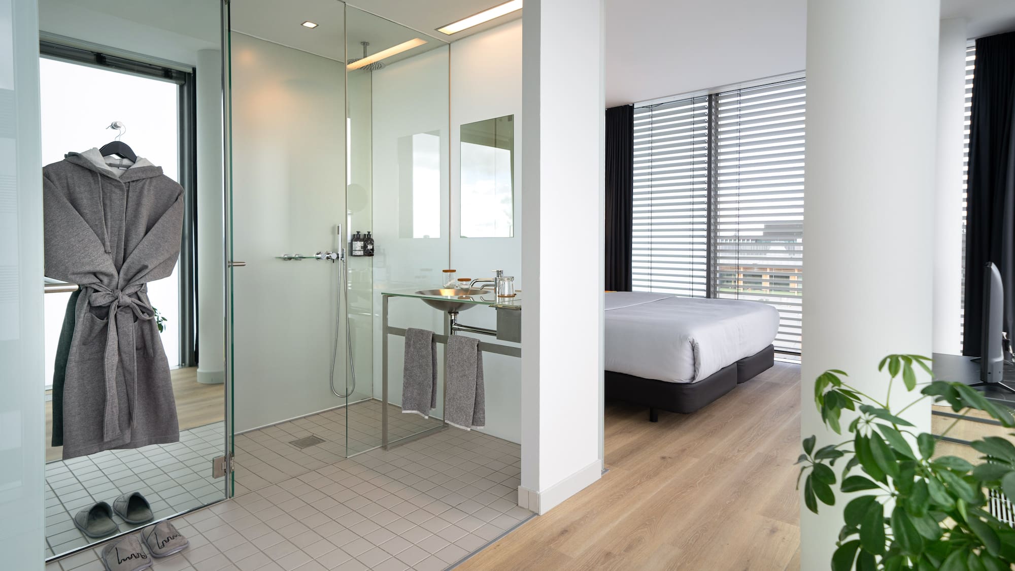 a bathroom with a glass shower and a bed