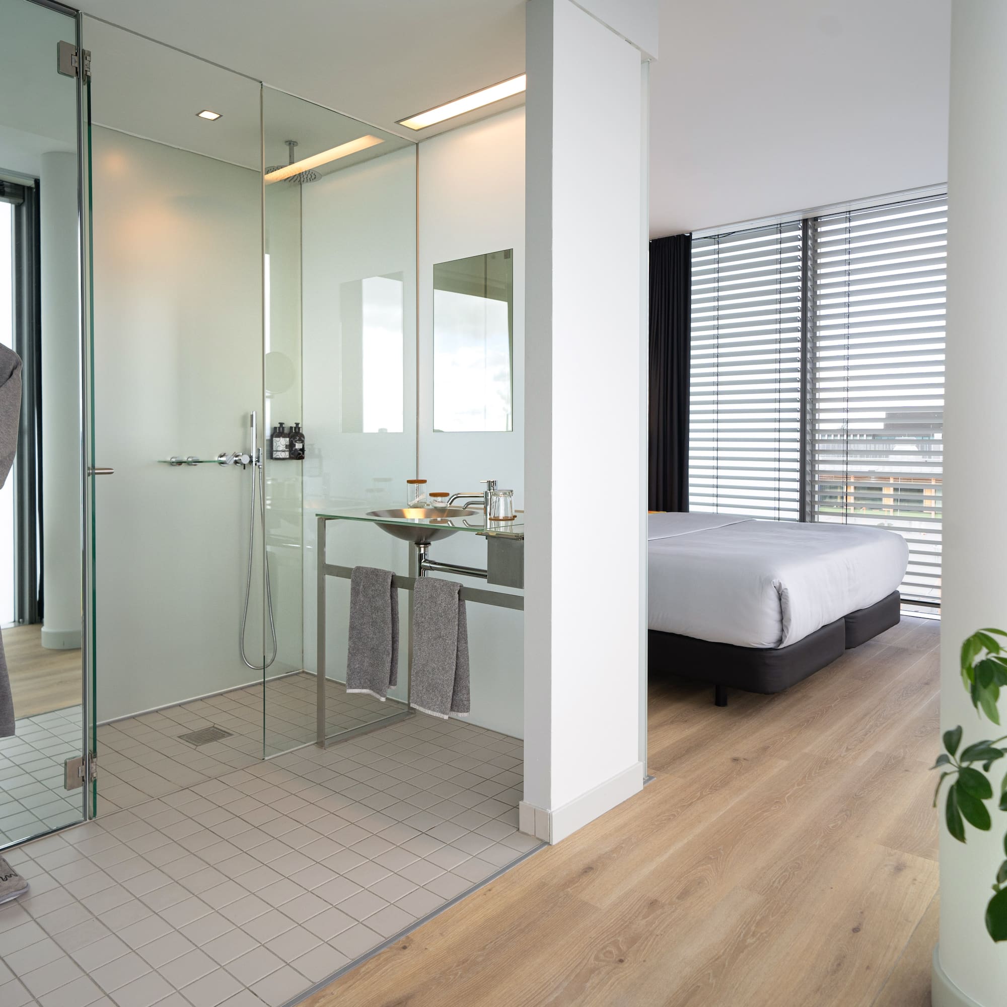 a bathroom with a glass shower and a bed