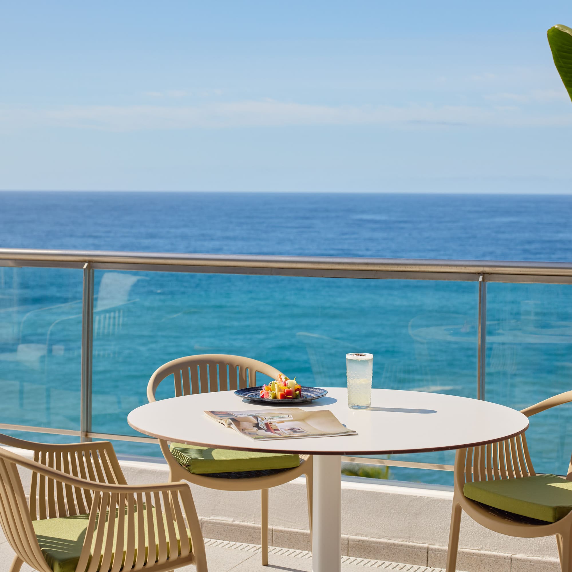 a table and chairs on a balcony overlooking the ocean