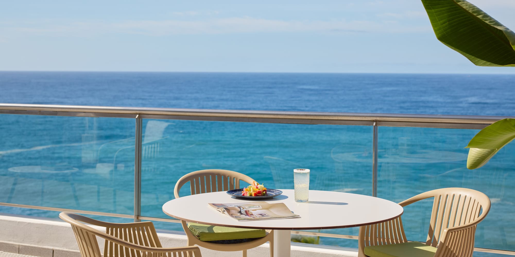 a table and chairs on a balcony overlooking the ocean