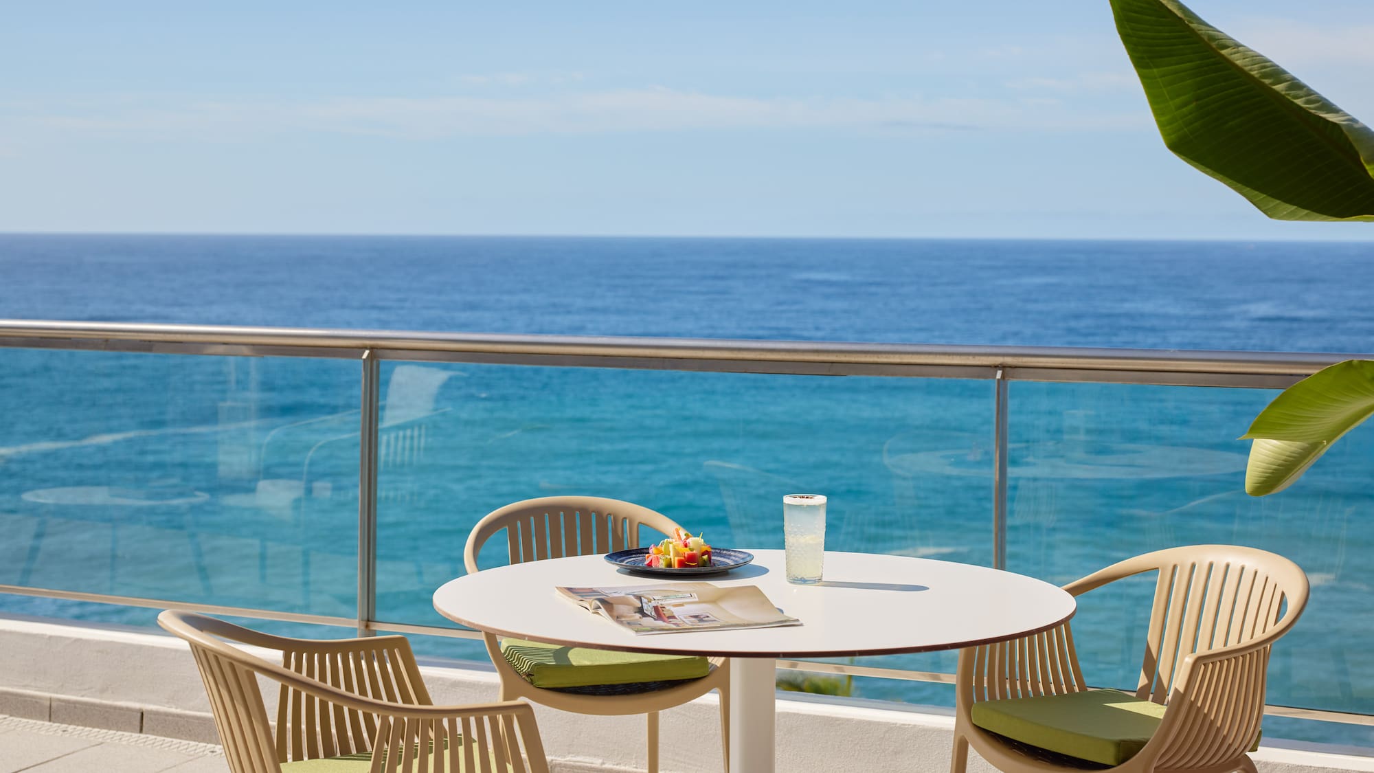 a table and chairs on a balcony overlooking the ocean